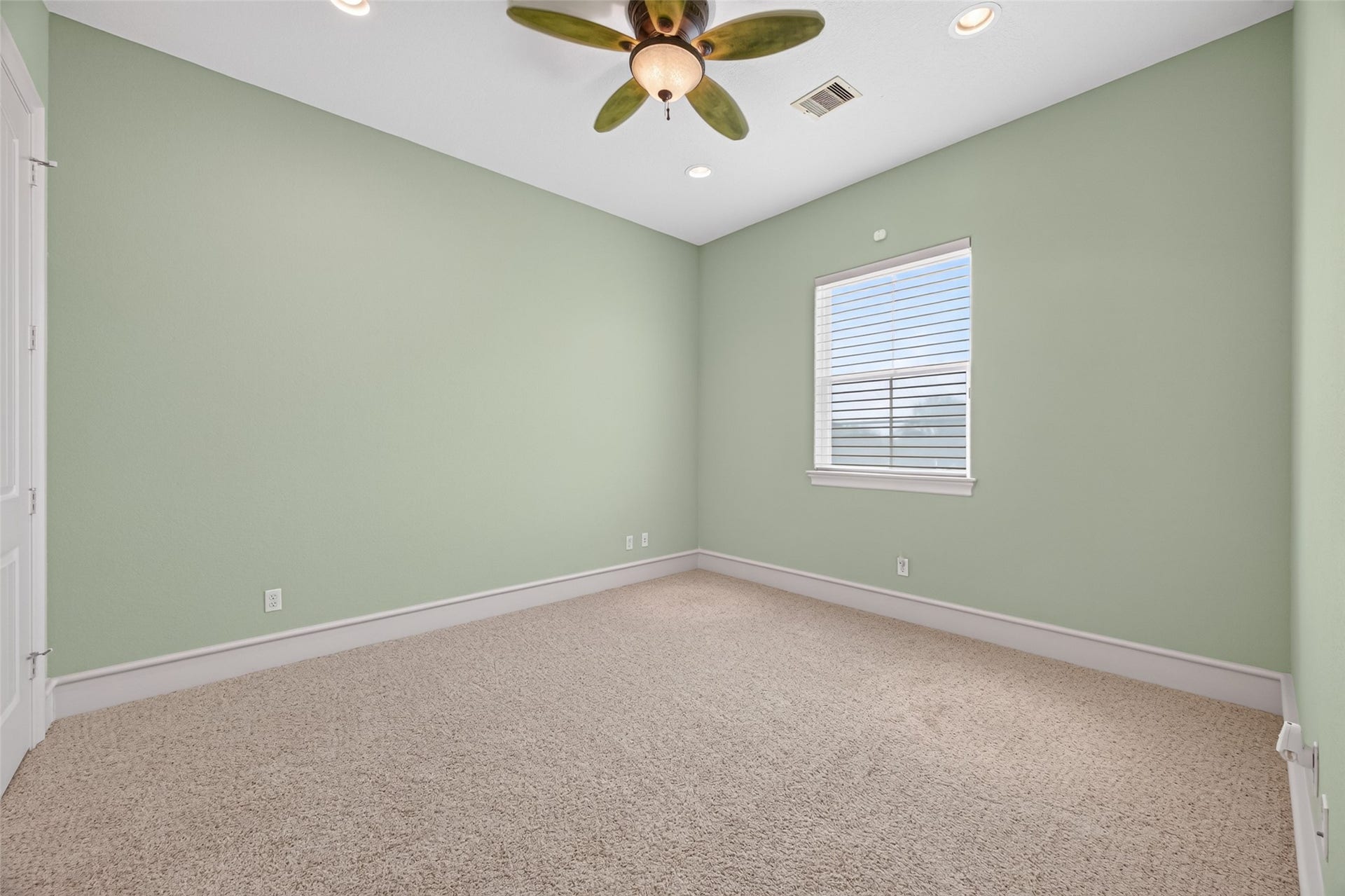 13 Sugarloaf, Hitchcock, TX 77563 Cozy bedroom with soft green walls, plush carpet, and a ceiling fan, offering a serene and inviting atmosphere.