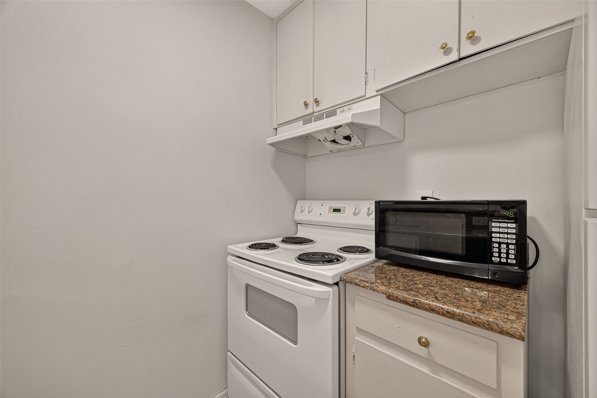 5353 Richmond Avenue, #12, Houston, TX 77056 Compact kitchen nook with an electric stove, granite countertop, and convenient overhead cabinets for storage.