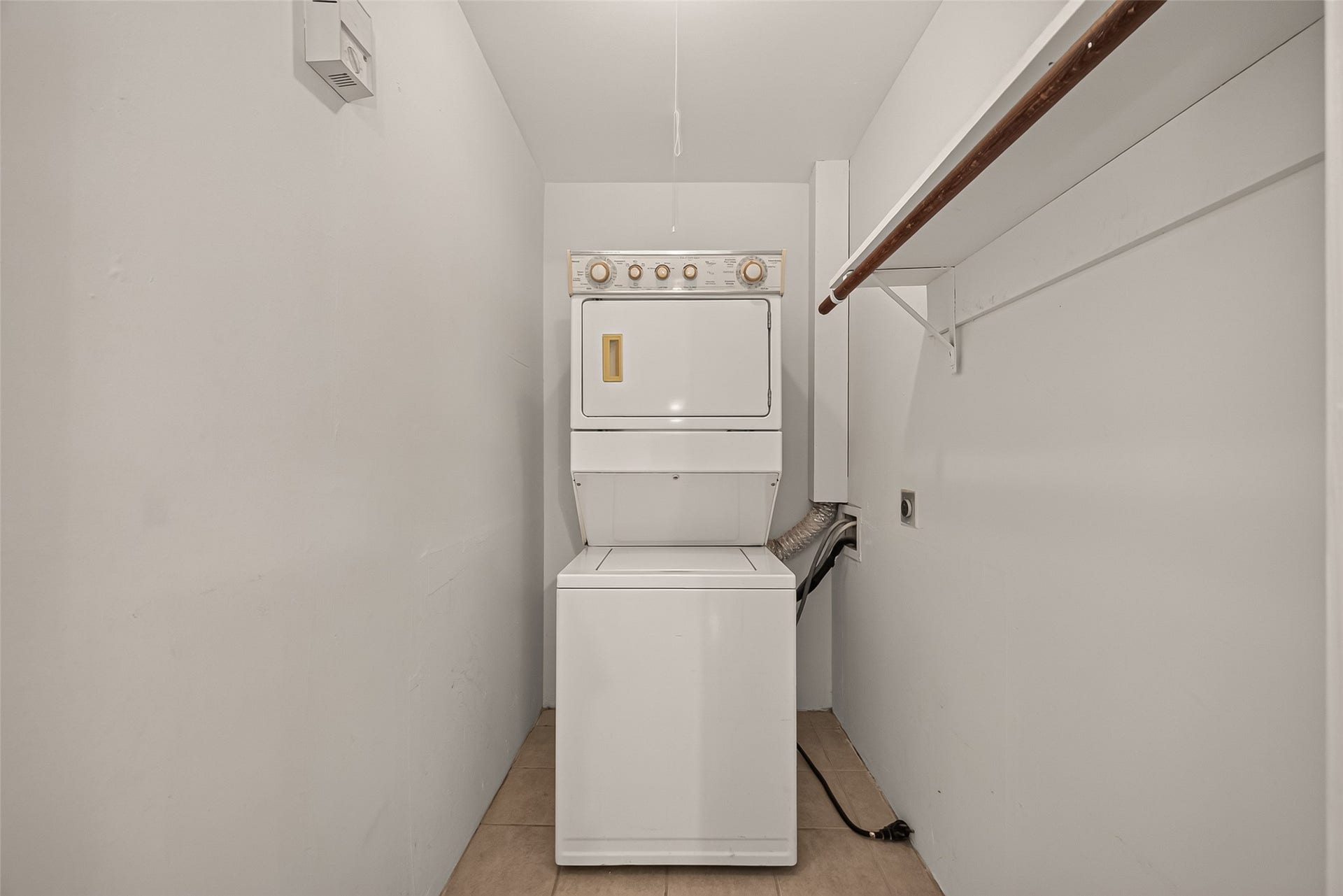 5353 Richmond Avenue, #12, Houston, TX 77056 Compact laundry area featuring a stacked washer and dryer, with an adjacent hanging rod for convenient clothing organization.