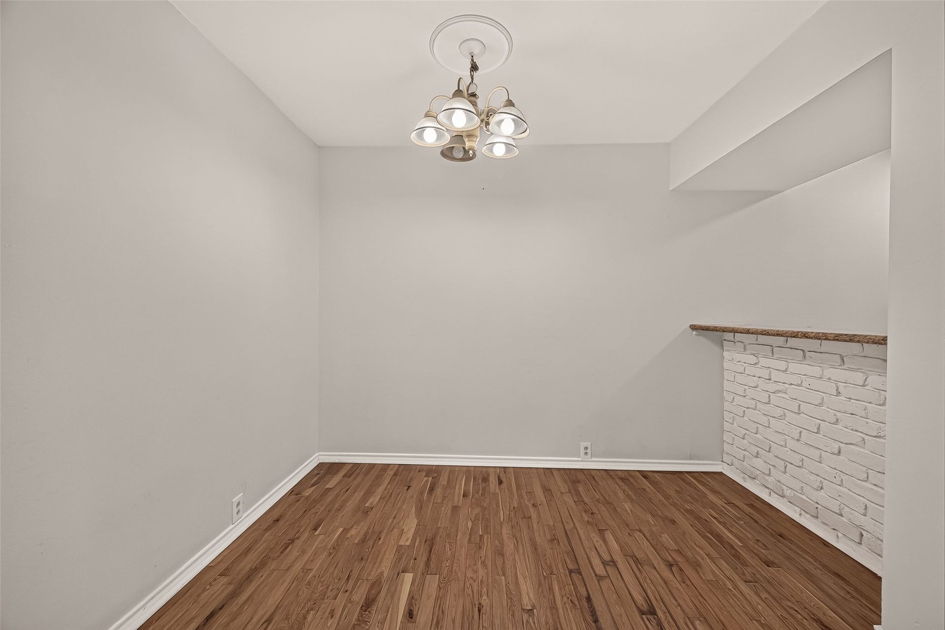5353 Richmond Avenue, #12, Houston, TX 77056 Charming dining area with warm hardwood floors and a stylish chandelier, featuring a cozy breakfast bar with a brick accent wall.