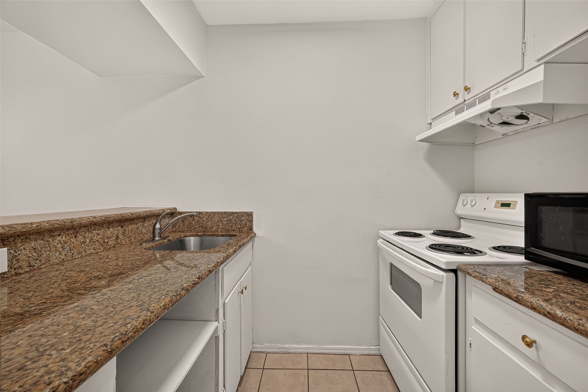 5353 Richmond Avenue, #12, Houston, TX 77056 Compact kitchen featuring sleek granite countertops, a white electric stove, and ample cabinetry for storage.