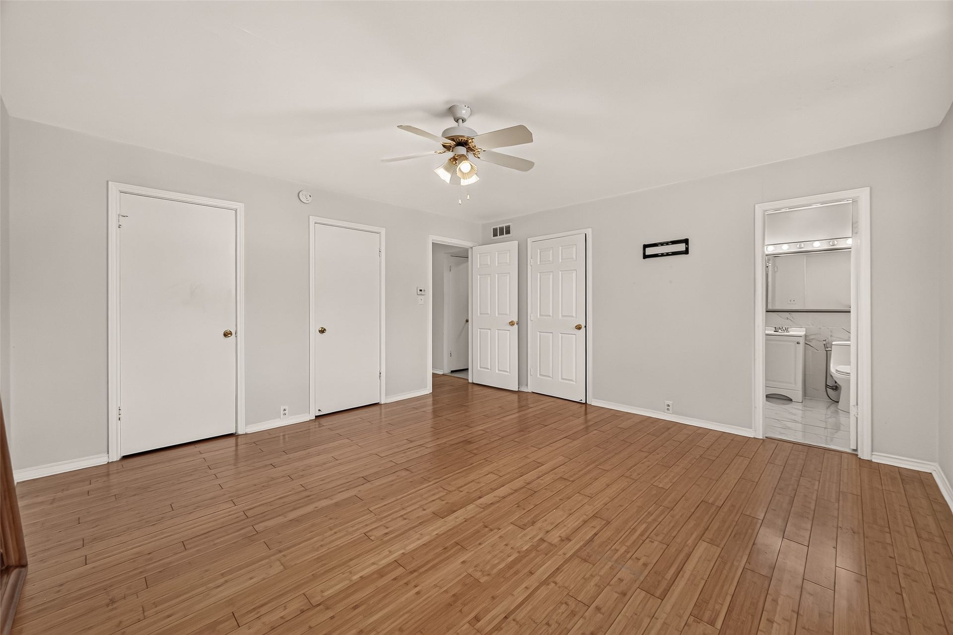 5353 Richmond Avenue, #12, Houston, TX 77056 Spacious room with polished hardwood floors, a ceiling fan, and ample closet space, leading to an en-suite bathroom.