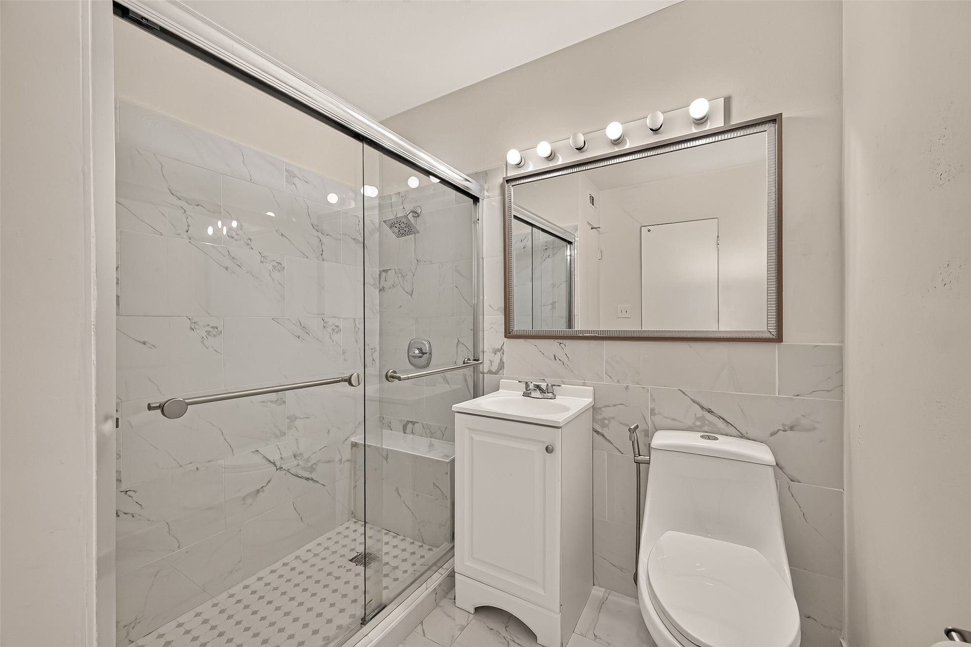 5353 Richmond Avenue, #12, Houston, TX 77056 Elegant bathroom featuring a sleek glass-enclosed shower with modern marble tile, a chic vanity with ample lighting, and a contemporary toilet for a sophisticated touch.