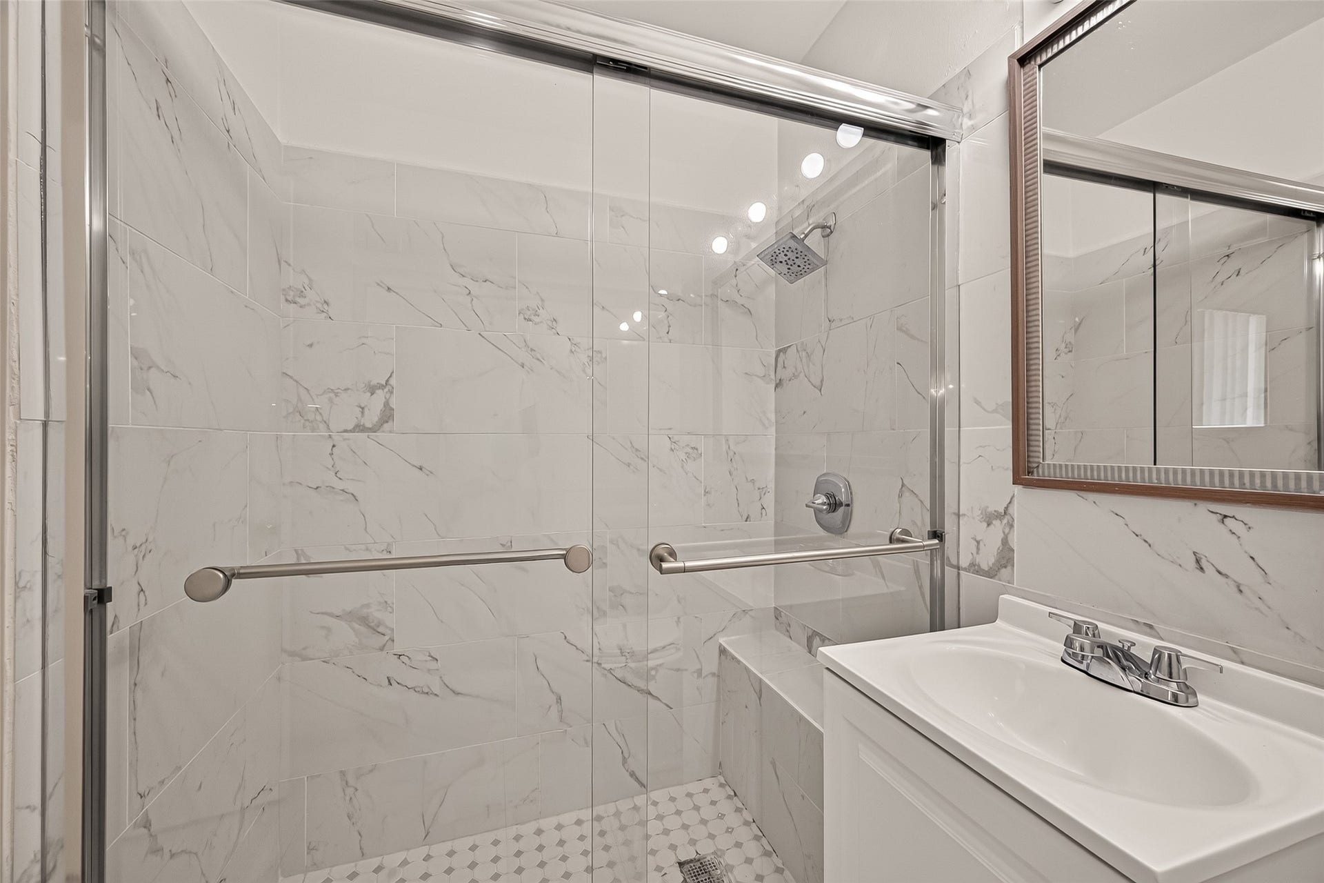 5353 Richmond Avenue, #12, Houston, TX 77056 Elegant bathroom featuring a spacious glass-enclosed shower with marble-style tiles and a sleek vanity, offering a modern and luxurious feel.