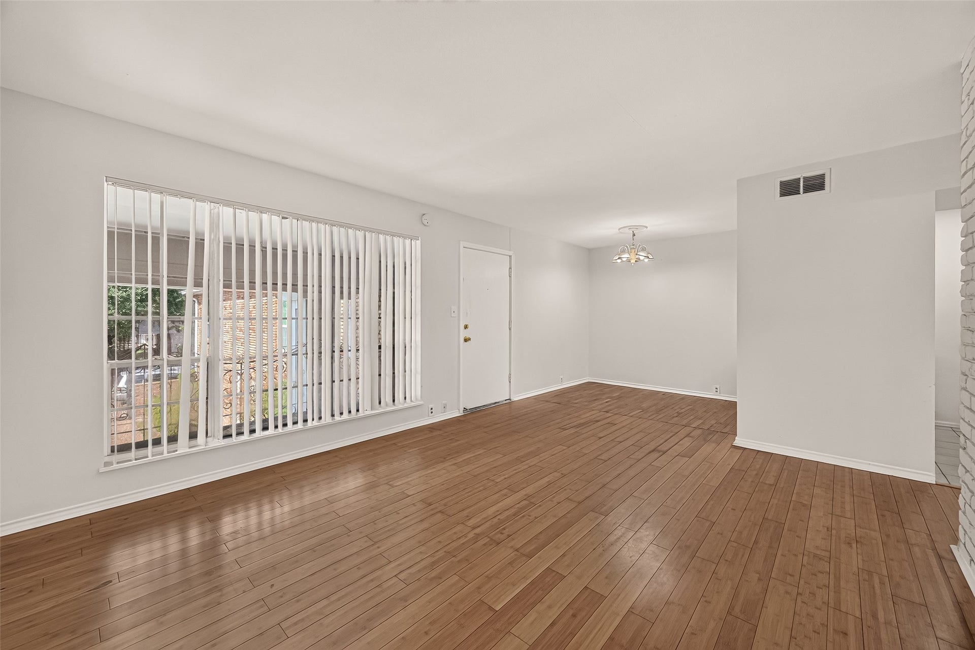 5353 Richmond Avenue, #12, Houston, TX 77056 Spacious living area with warm wooden flooring and ample natural light from a large window, creating an inviting atmosphere.