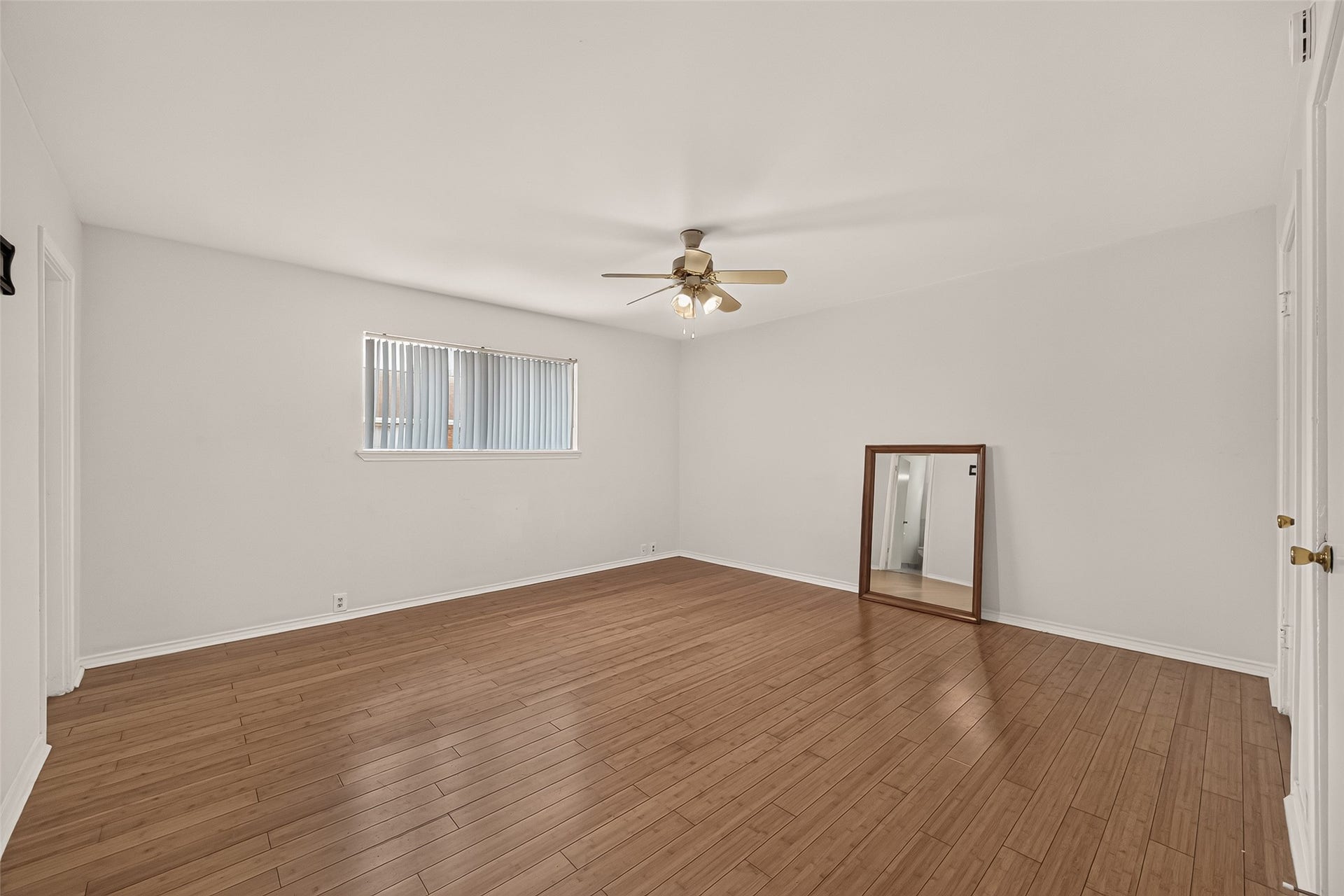 5353 Richmond Avenue, #12, Houston, TX 77056 Spacious room with elegant wood flooring, abundant natural light from a large window, and a ceiling fan for comfort.