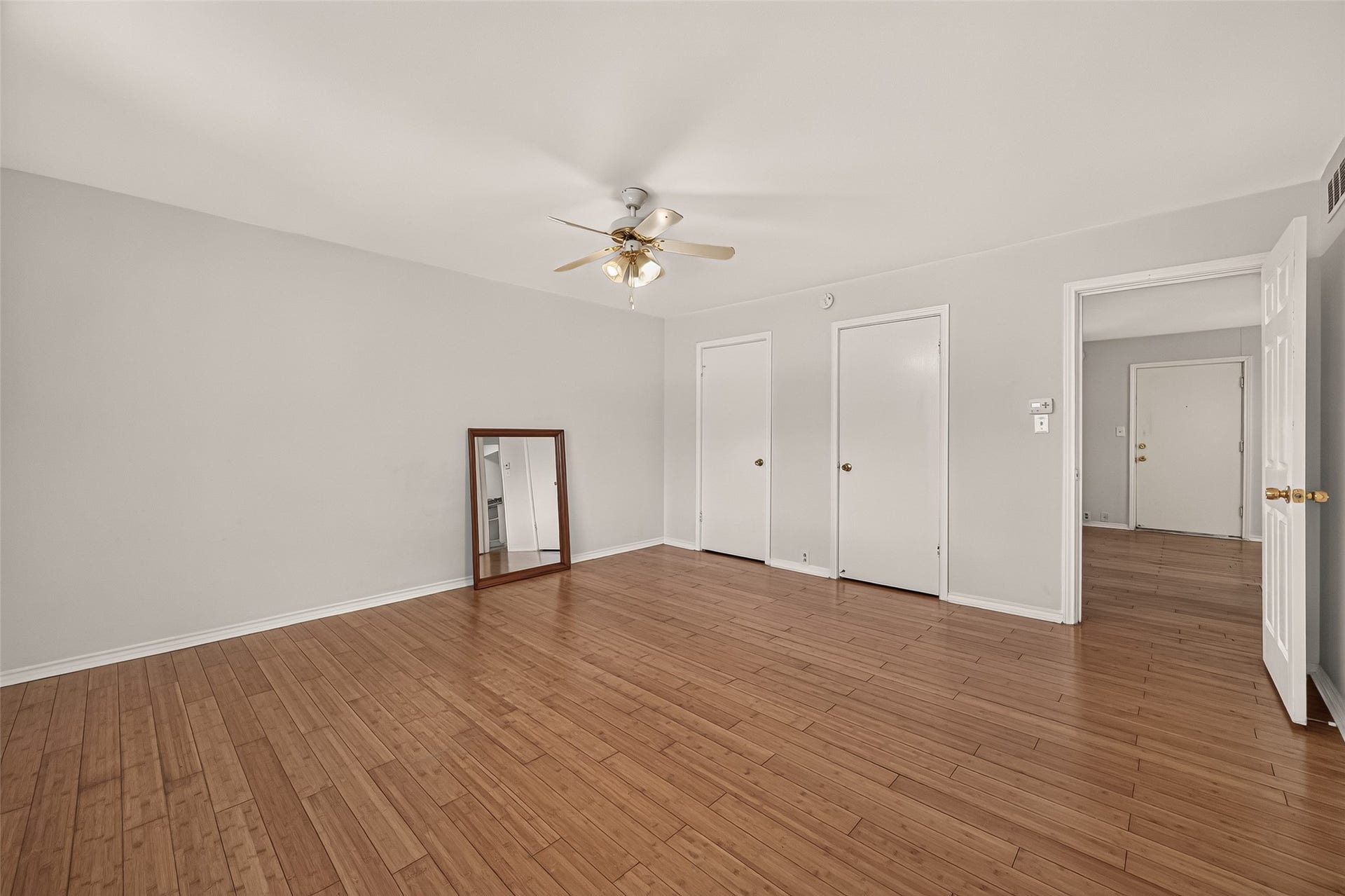 5353 Richmond Avenue, #12, Houston, TX 77056 Spacious room with elegant hardwood flooring, neutral walls, and a ceiling fan, offering ample natural light and versatile layout options.