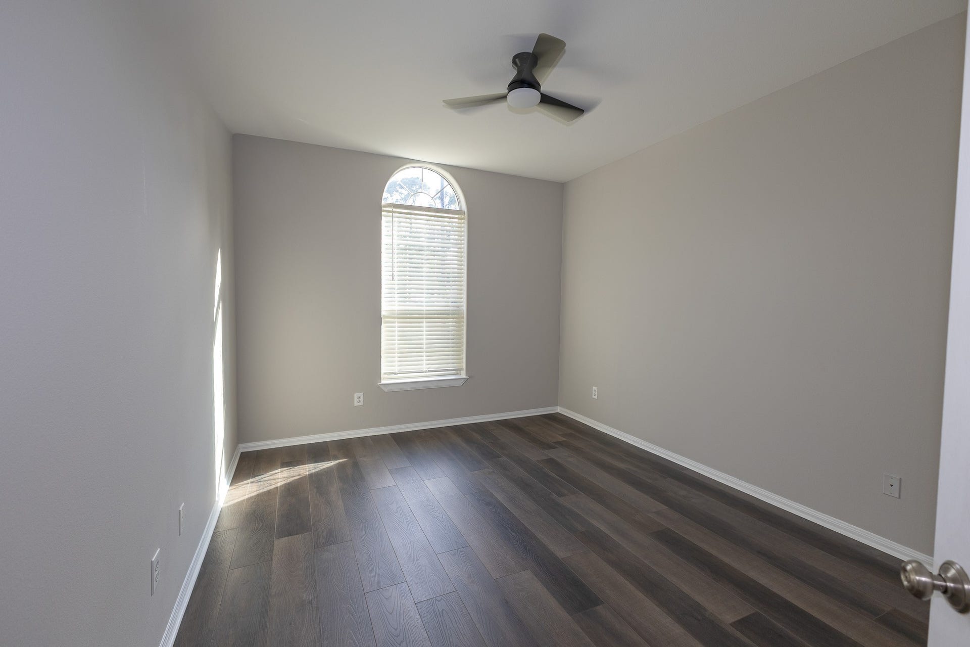 3302 Royal Oaks Drive, Spring, TX 77380 Bright and inviting bedroom featuring beautiful new flooring, fresh neutral paint, and a charming arched window that fills the space with natural light. A modern ceiling fan adds comfort and style!