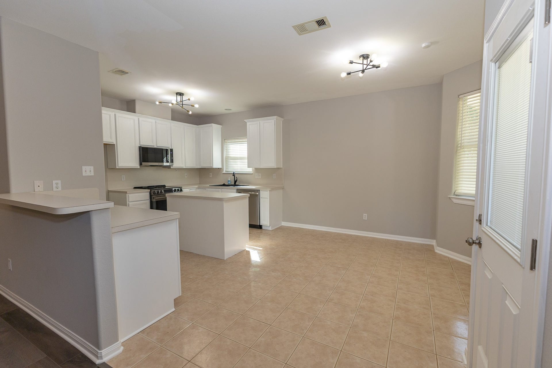 3302 Royal Oaks Drive, Spring, TX 77380 Spacious open-concept kitchen and breakfast area featuring crisp white cabinetry, modern lighting, and a convenient island. The seamless layout offers plenty of room for everyday dining, gathering, and entertaining!