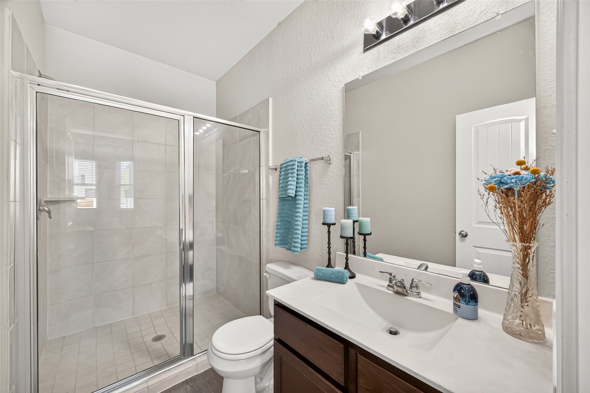 13405 Cannon Creek Court, Willis, TX 77378 Primary bath offering bright and modern bathroom featuring a spacious glass-enclosed shower, elegant vanity with stylish lighting, and tasteful decor accents.