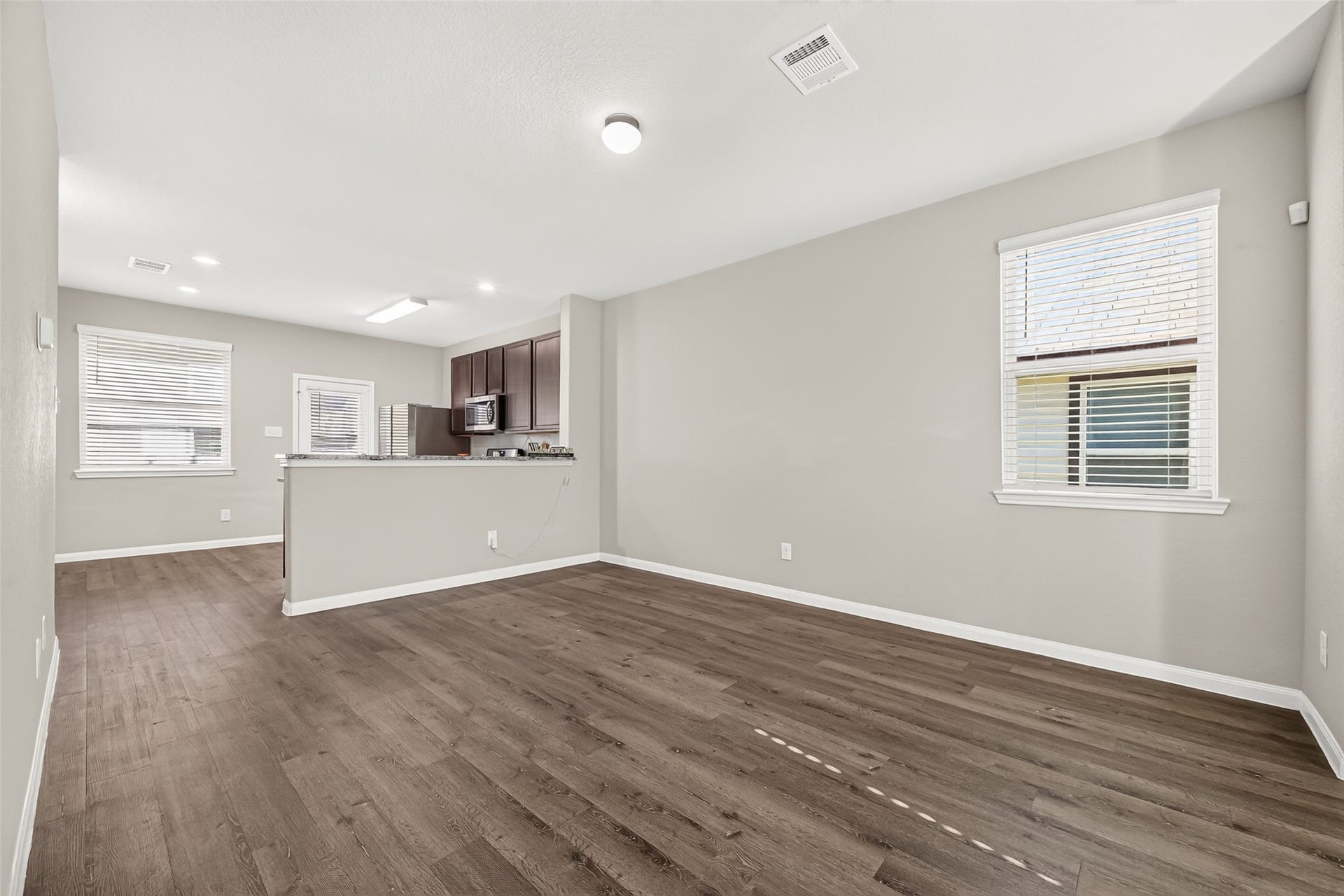 13405 Cannon Creek Court, Willis, TX 77378 Spacious open-concept living area with elegant flooring and abundant natural light, seamlessly flowing into a modern kitchen with dark cabinetry.