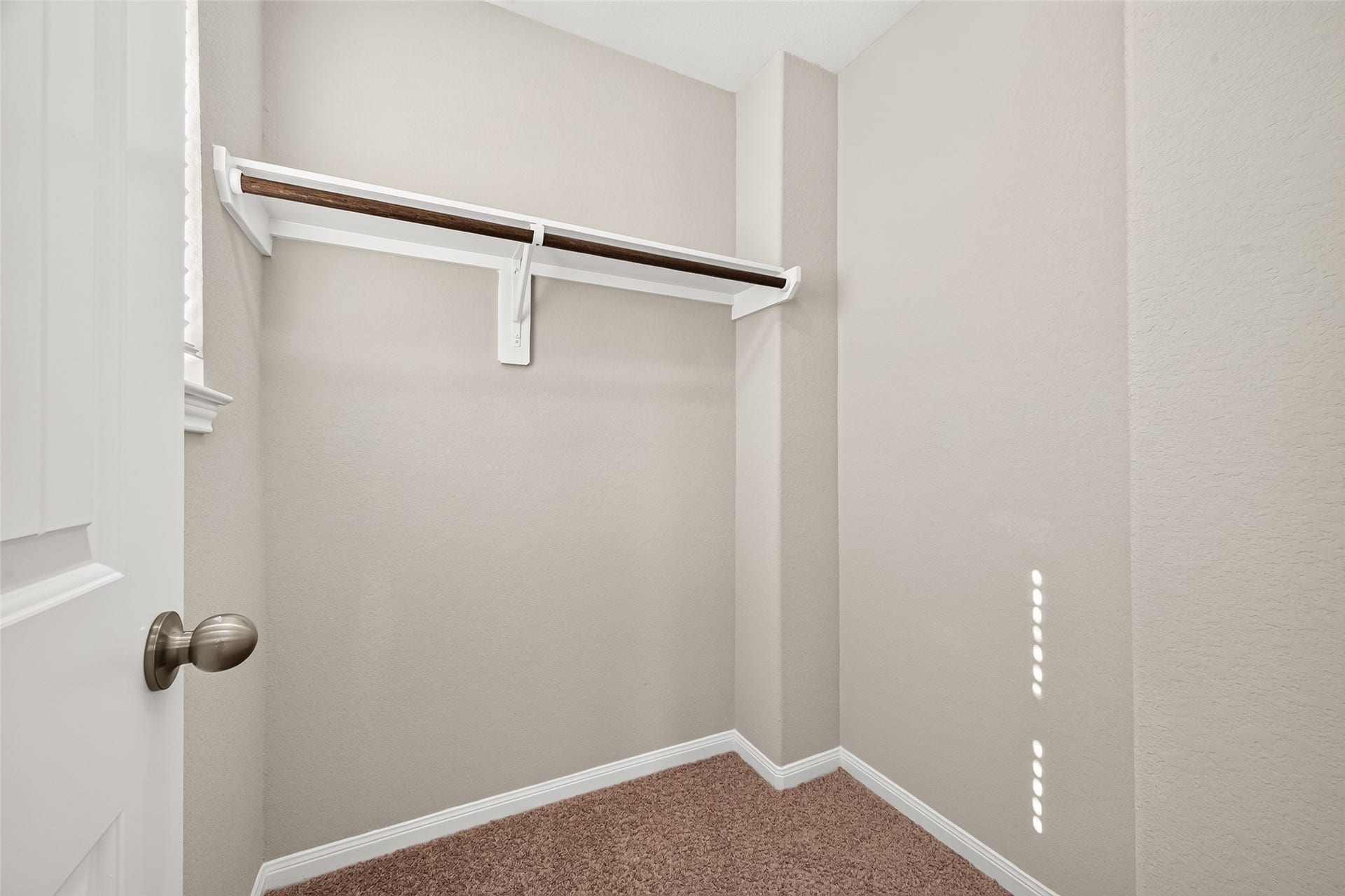 13405 Cannon Creek Court, Willis, TX 77378 Good size walk-in closet with a sturdy wooden rod for ample hanging storage, complemented by soft carpeting and neutral walls.