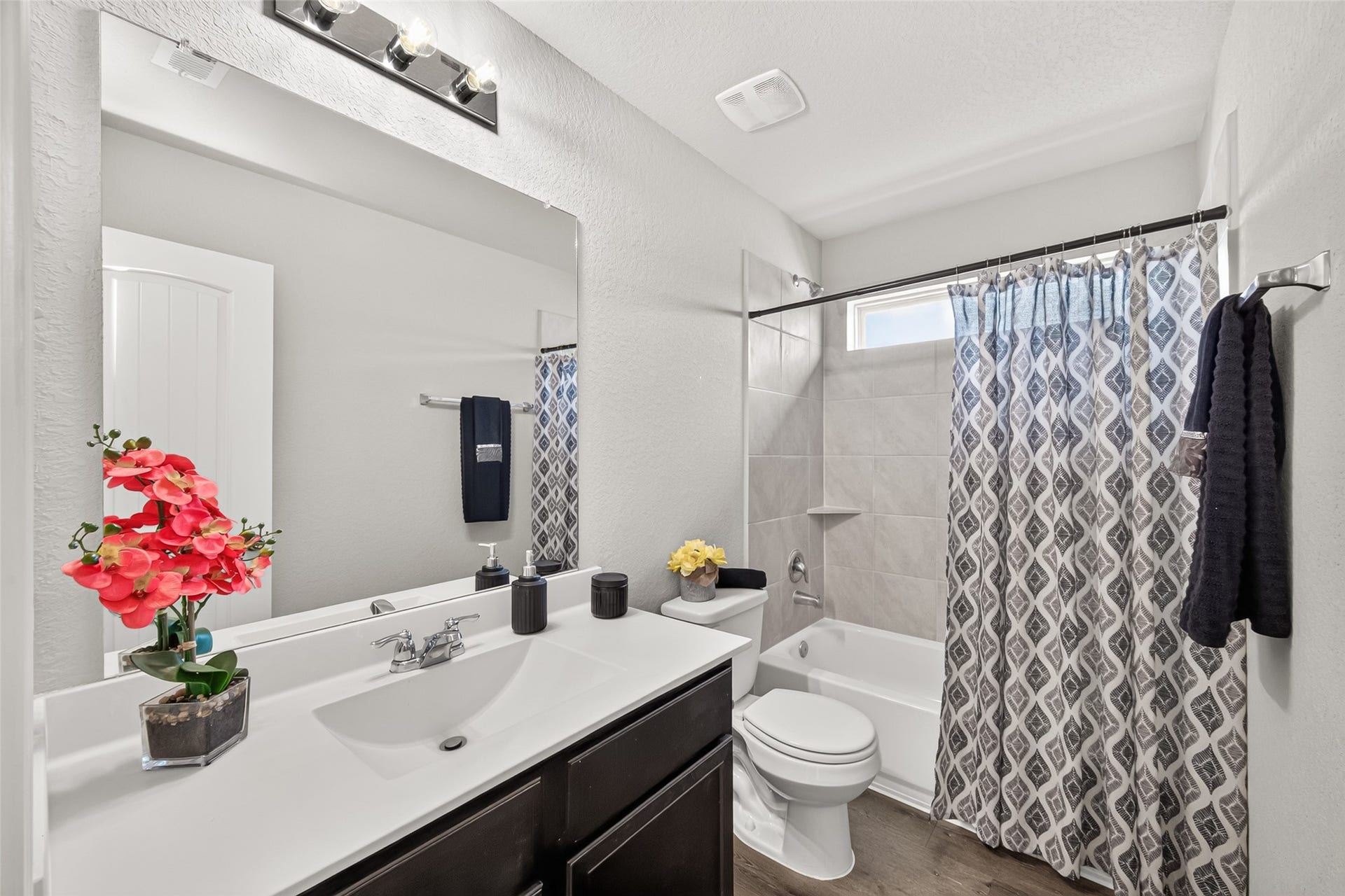 13405 Cannon Creek Court, Willis, TX 77378 Modern bathroom with a stylish vanity, chic lighting, and a bathtub with an elegant patterned shower curtain.