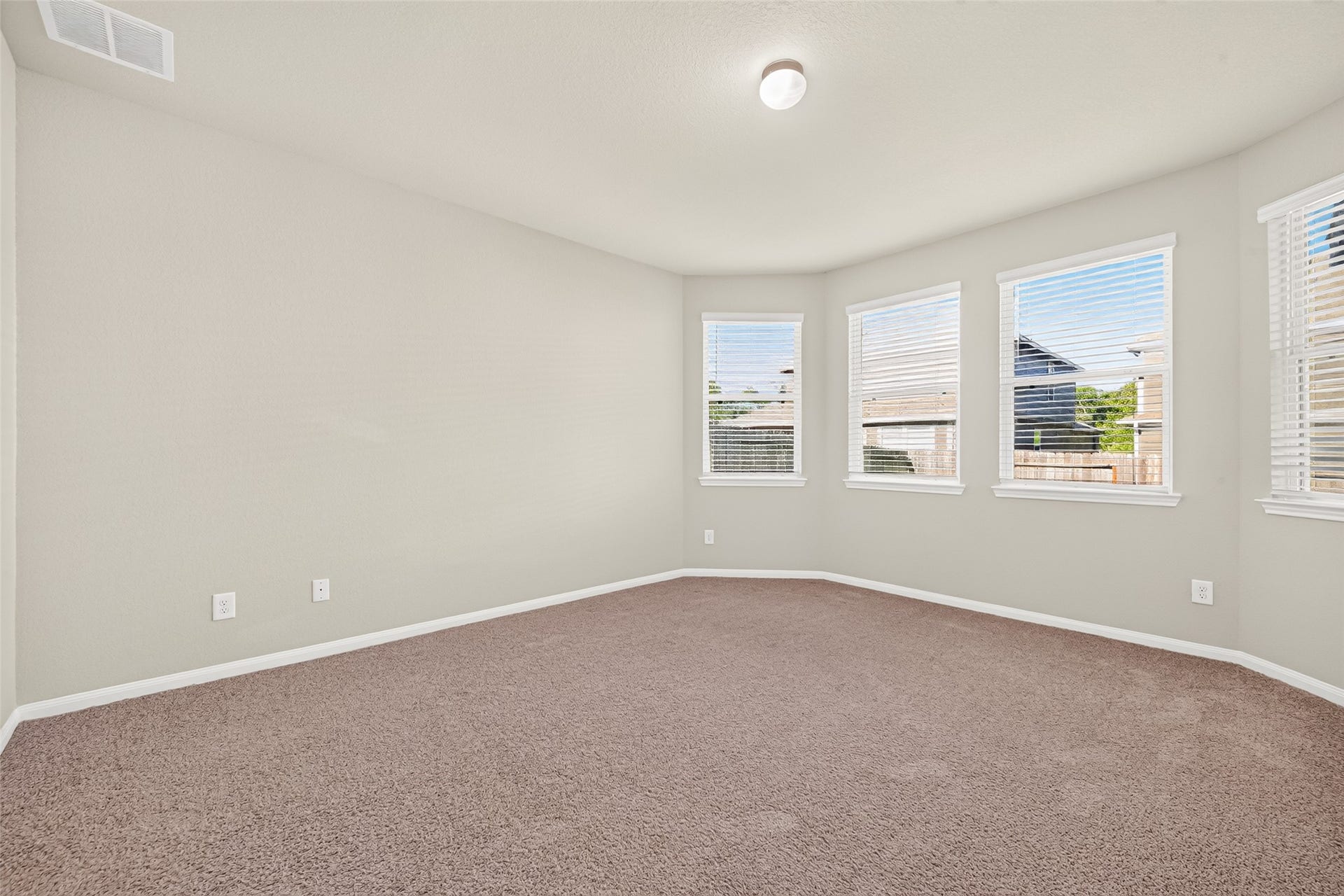 13405 Cannon Creek Court, Willis, TX 77378 Primary bedroom with extended window space for a reading nook. Light-filled room with neutral walls, plush carpet, and multiple large windows offering a serene view.