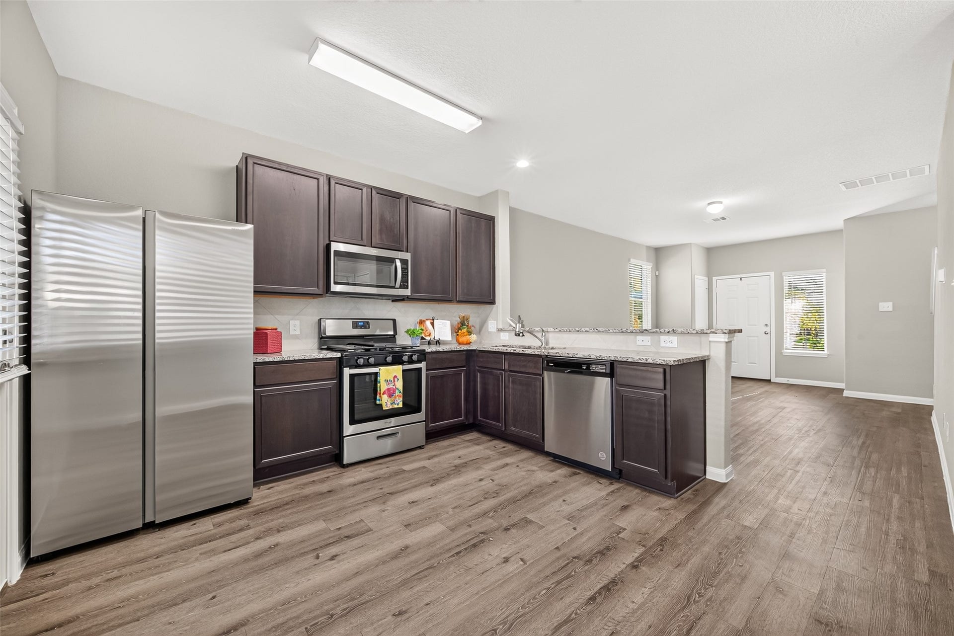 13405 Cannon Creek Court, Willis, TX 77378 Modern kitchen with stainless steel appliances, dark cabinetry, and a spacious open layout leading into a bright living area.