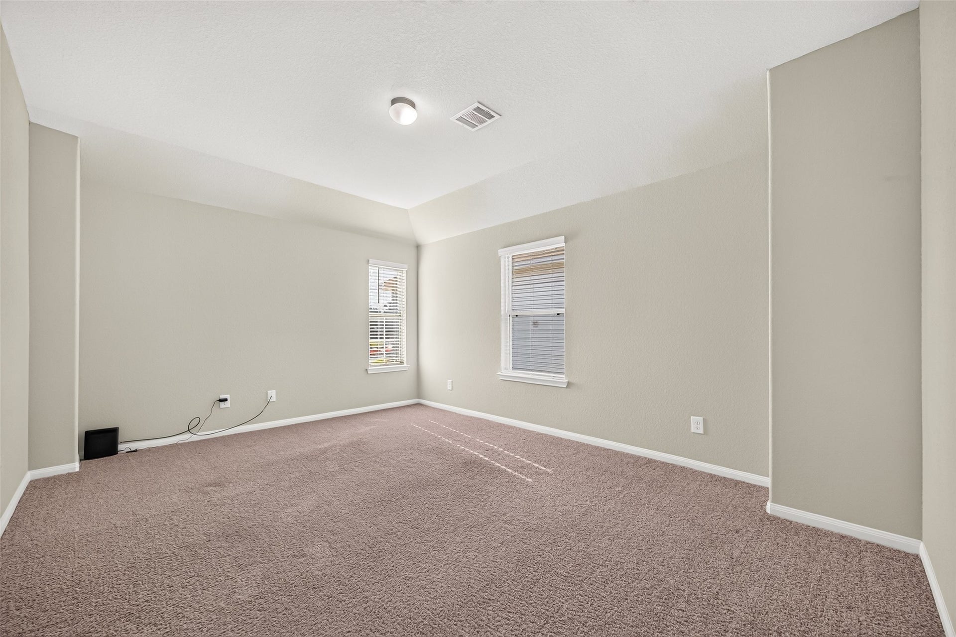 13405 Cannon Creek Court, Willis, TX 77378 HUGE game room with neutral tones, plush carpeting, and two large windows for natural light.