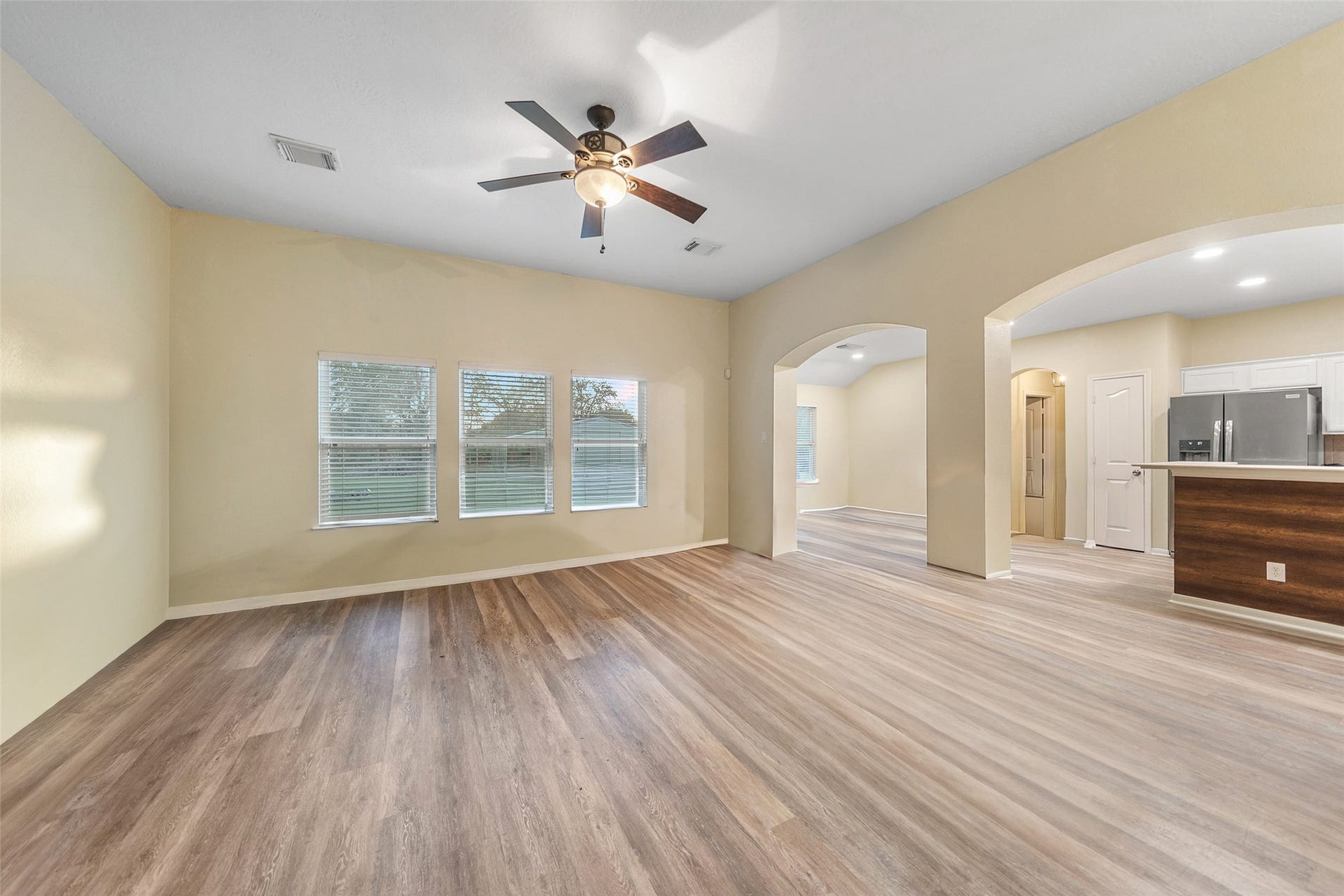 Expansive living space with arched openings, ceiling fan, and flexible layout options.
