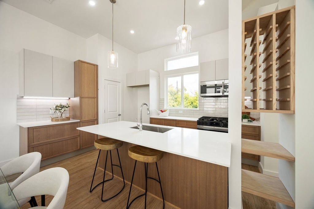 Beautiful kitchen featuring quartz countertops, a custom wine rack, stainless steel appliances, and abundant cabinet space.