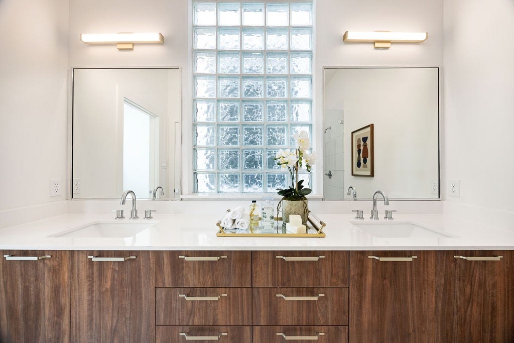 Elegant primary bath featuring dual vanities and a beautiful glass block window that fills the space with natural light.