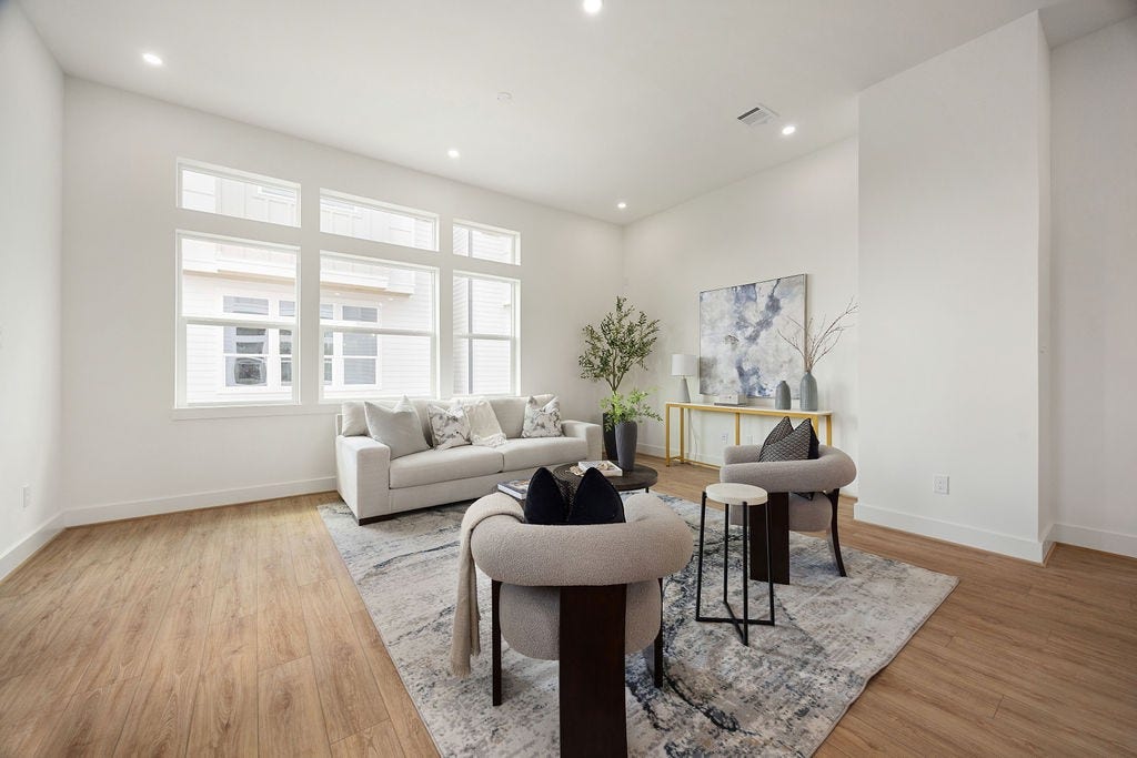Another view of the spacious living room showcasing abundant natural light.
