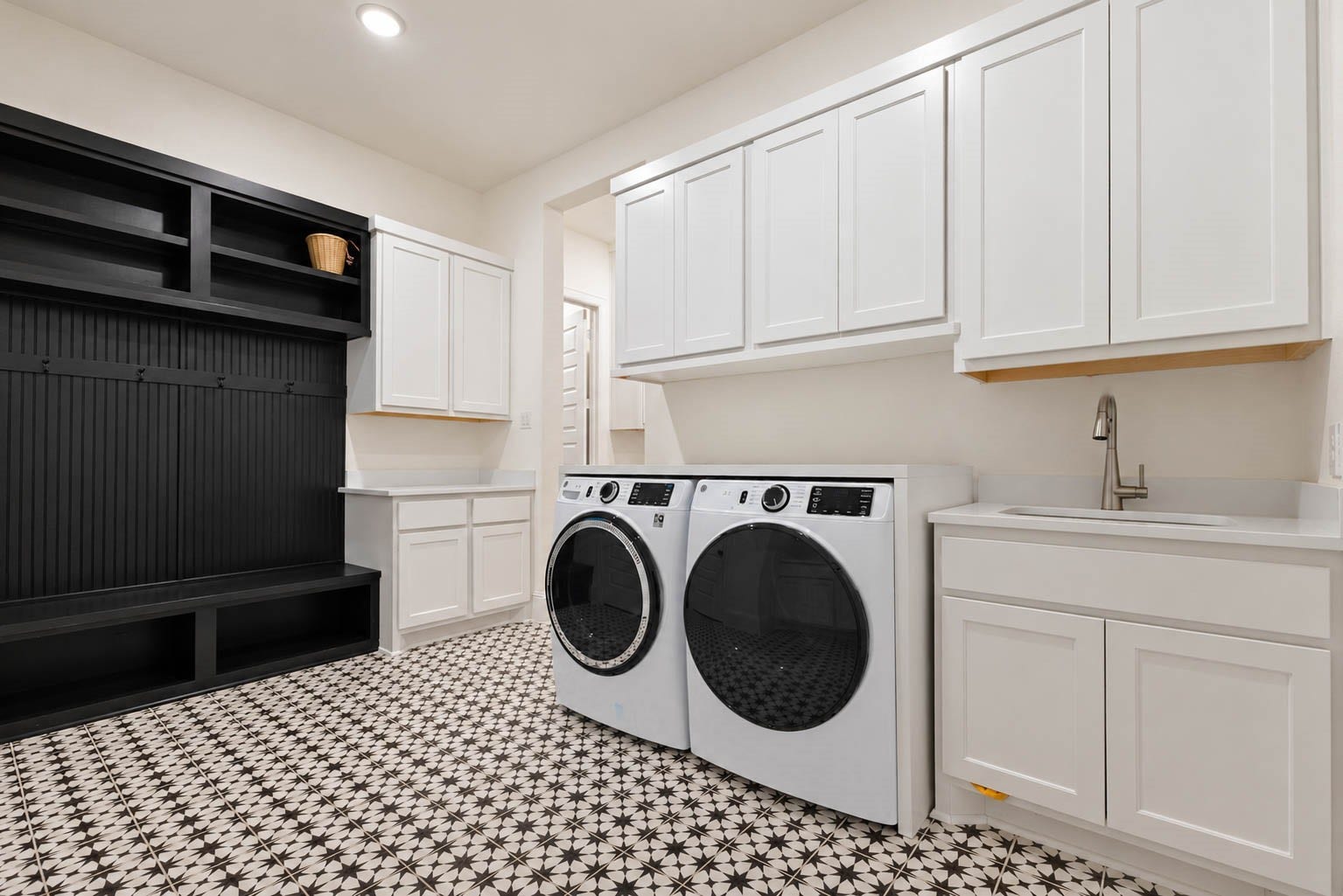 4839 Summer Place Court, Fulshear, TX 77441 Stylish laundry room featuring modern appliances, ample cabinetry, a convenient sink, and a chic black and white tile floor. Cute accent with black mud room coming from the garage.