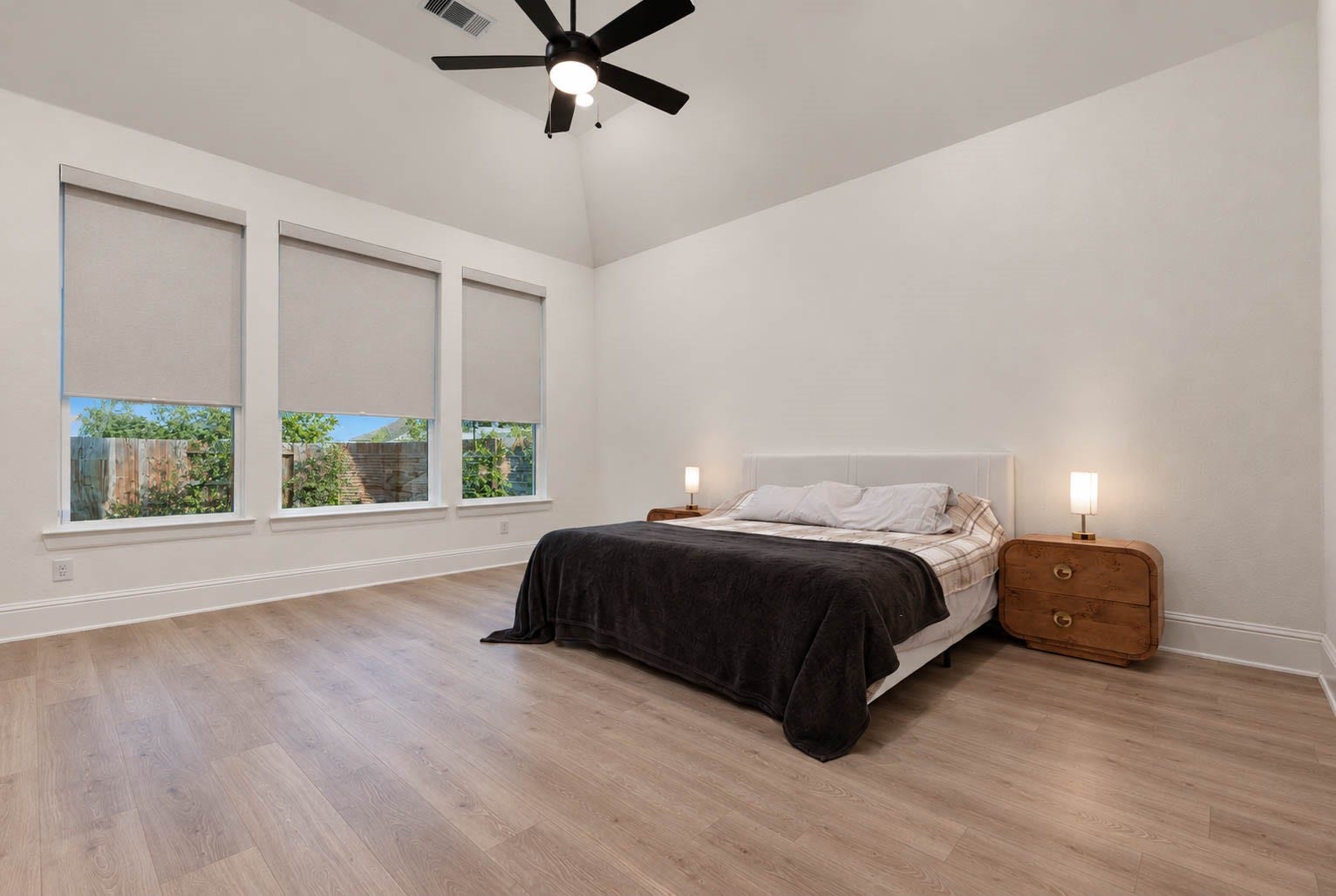 4839 Summer Place Court, Fulshear, TX 77441 Spacious primary bedroom with high ceilings, large windows with custom blinds, and elegant wood flooring, featuring a modern ceiling fan and ample natural light.