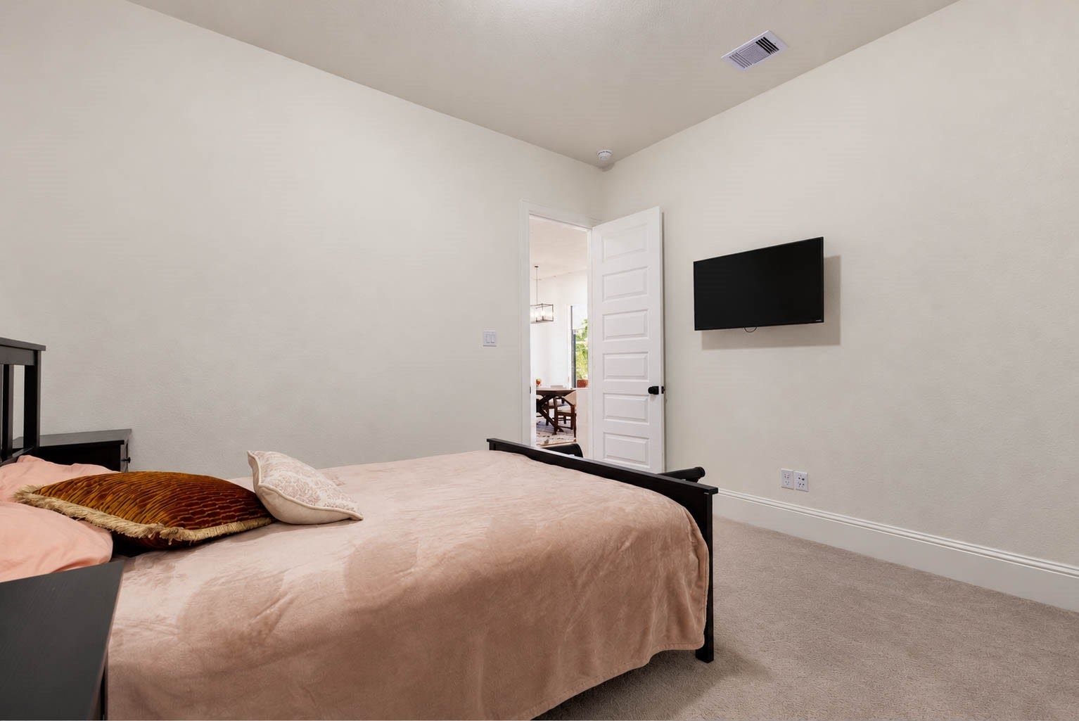 4839 Summer Place Court, Fulshear, TX 77441 Cozy bedroom with neutral tones, featuring a wall-mounted TV and a view into the en suite bathroom.