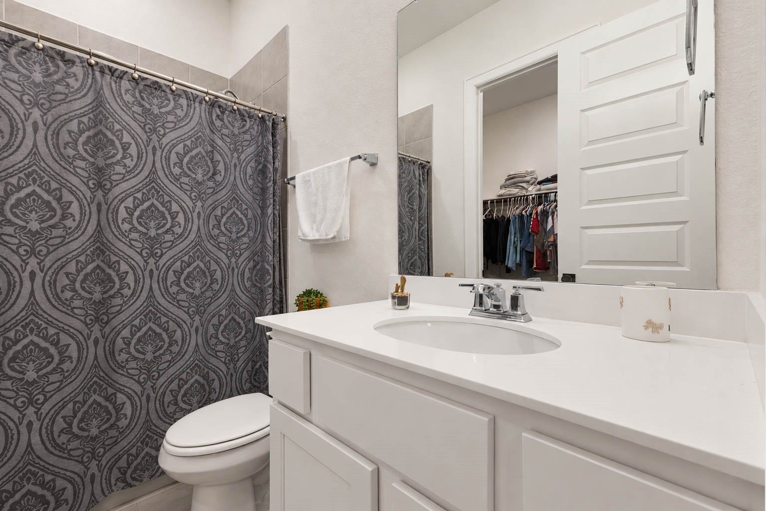 4839 Summer Place Court, Fulshear, TX 77441 Chic bathroom with a sleek white vanity, elegant patterned shower curtain, and ample storage, offering a modern and functional space.