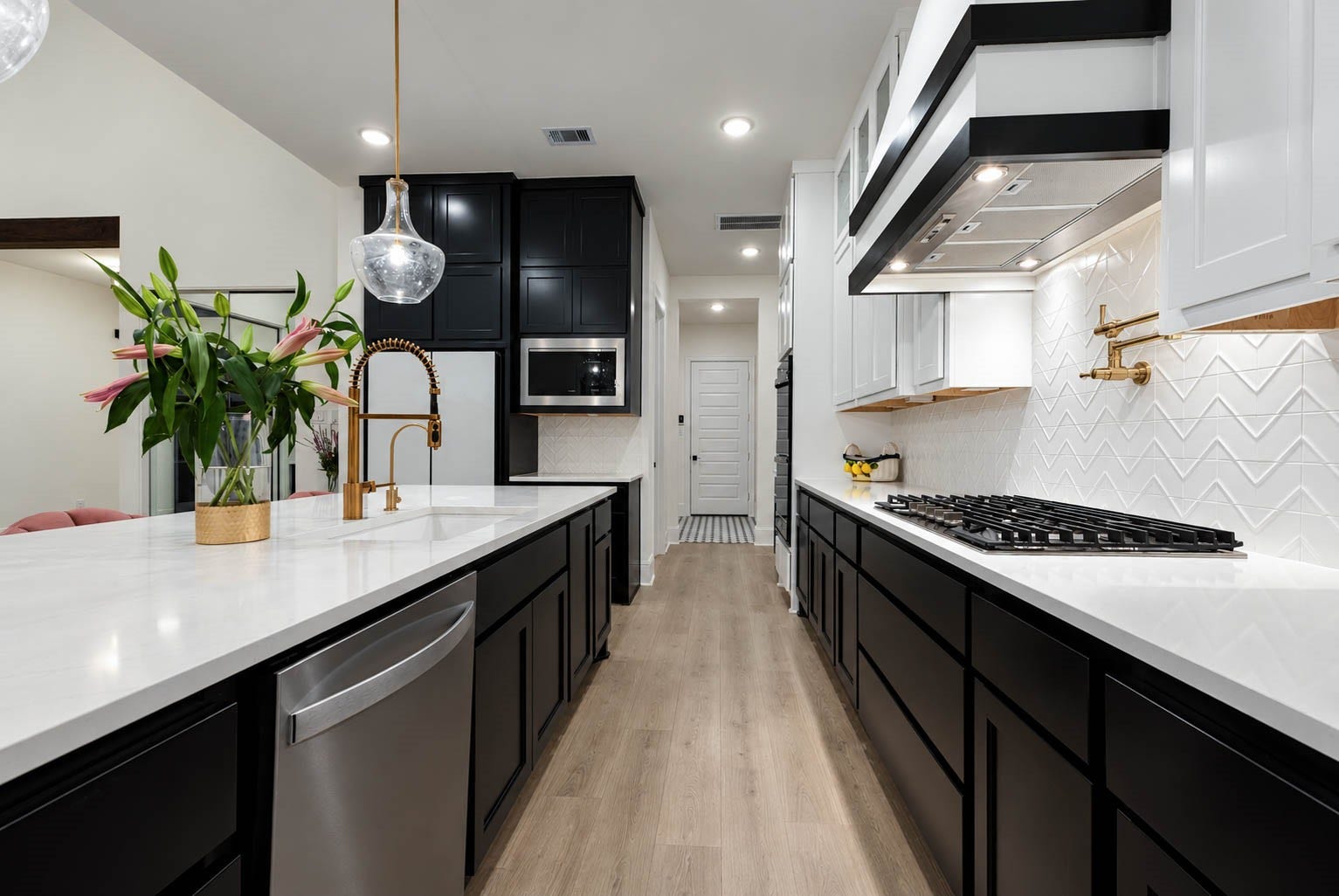 4839 Summer Place Court, Fulshear, TX 77441 Sleek modern kitchen featuring a spacious design with elegant black and white cabinetry, a stylish gold faucet, and a chic herringbone backsplash. Look at the pot filler in golden tones, just elegant and functional.