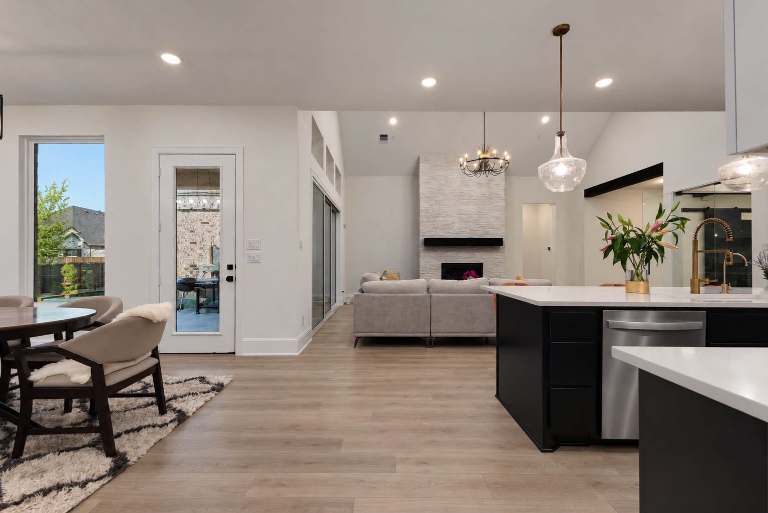 4839 Summer Place Court, Fulshear, TX 77441 Stunning open-concept living space featuring a modern kitchen with sleek countertops, elegant pendant lighting, and a cozy living area with a stylish fireplace. Perfect for entertaining and relaxation.