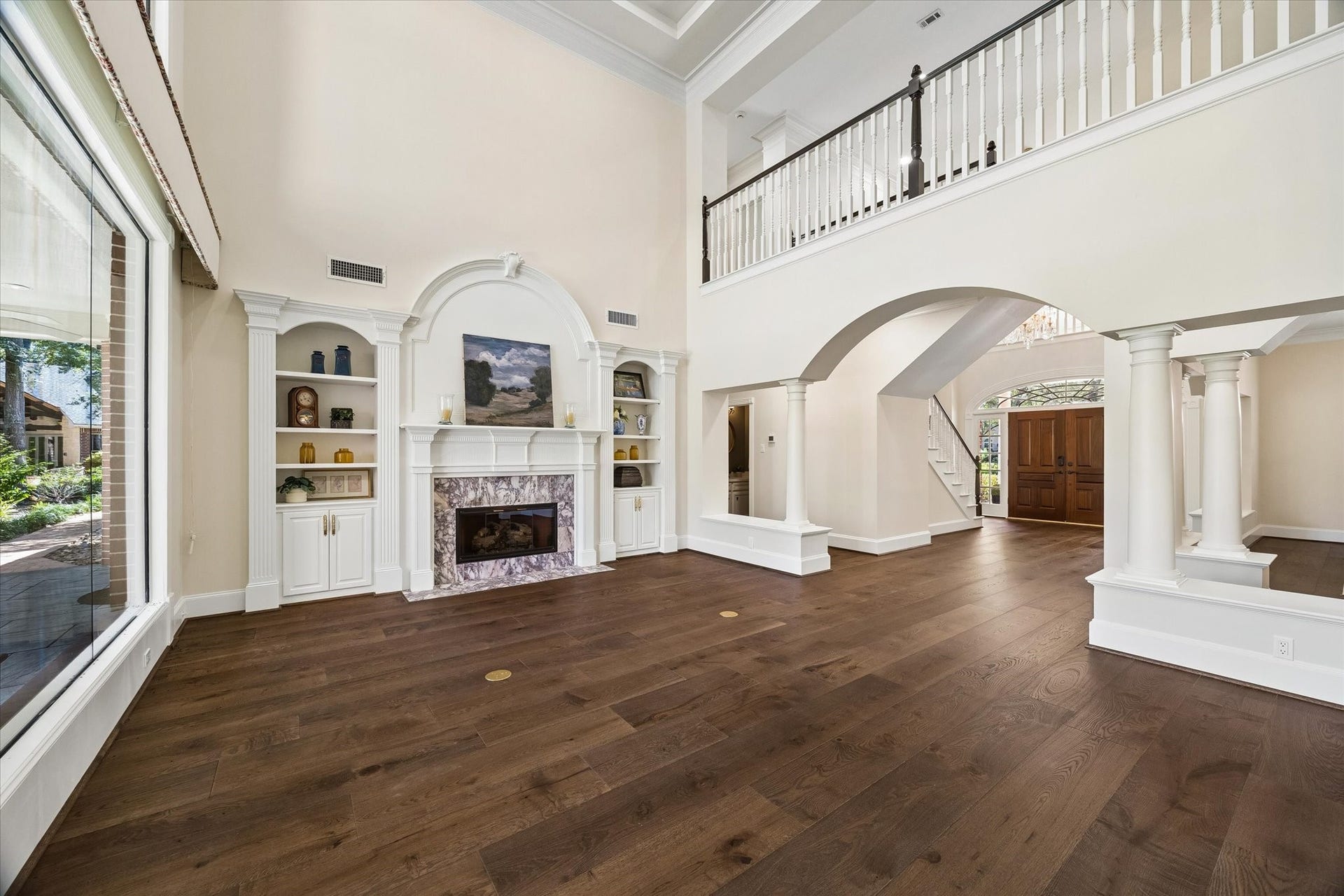 7 Pastoral Pond Circle, The Woodlands, TX 77380 Stunning two-story living room featuring an elegant marble fireplace and custom built-in cabinetry.