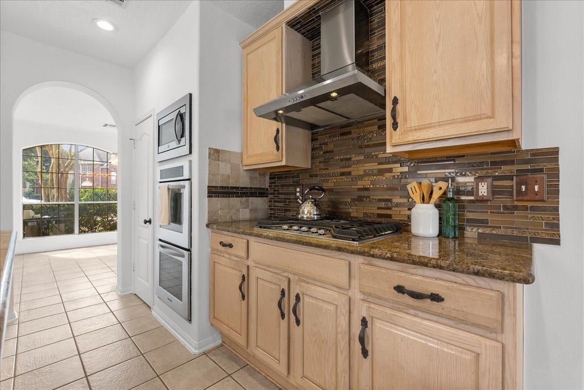 311 Lake Front Drive, League City, TX 77573 This kitchen is ready for you and your gourmet meals!! Gas cooktop with a stainless vent hood, mosaic tile backsplash, and double wall ovens.