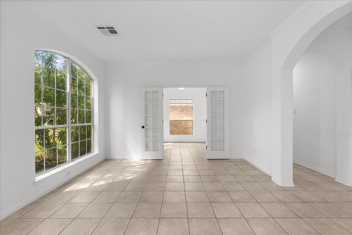 311 Lake Front Drive, League City, TX 77573 Formal living room with a large arched window and French doors leading to the study/bedroom.