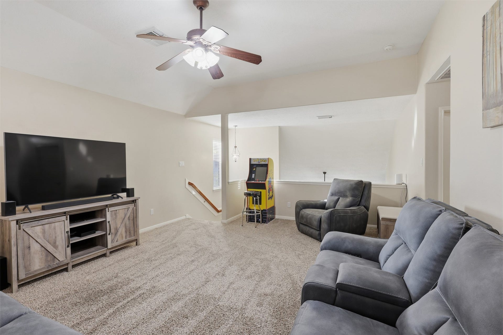 11404 Summit Bay Drive, Pearland, TX 77584 Another view of the generous upstairs game room showcases its versatile layout, comfortable seating area, plush carpeting, ceiling fan, and large windows. A wonderful space for entertaining guests or creating a dedicated family recreation area.