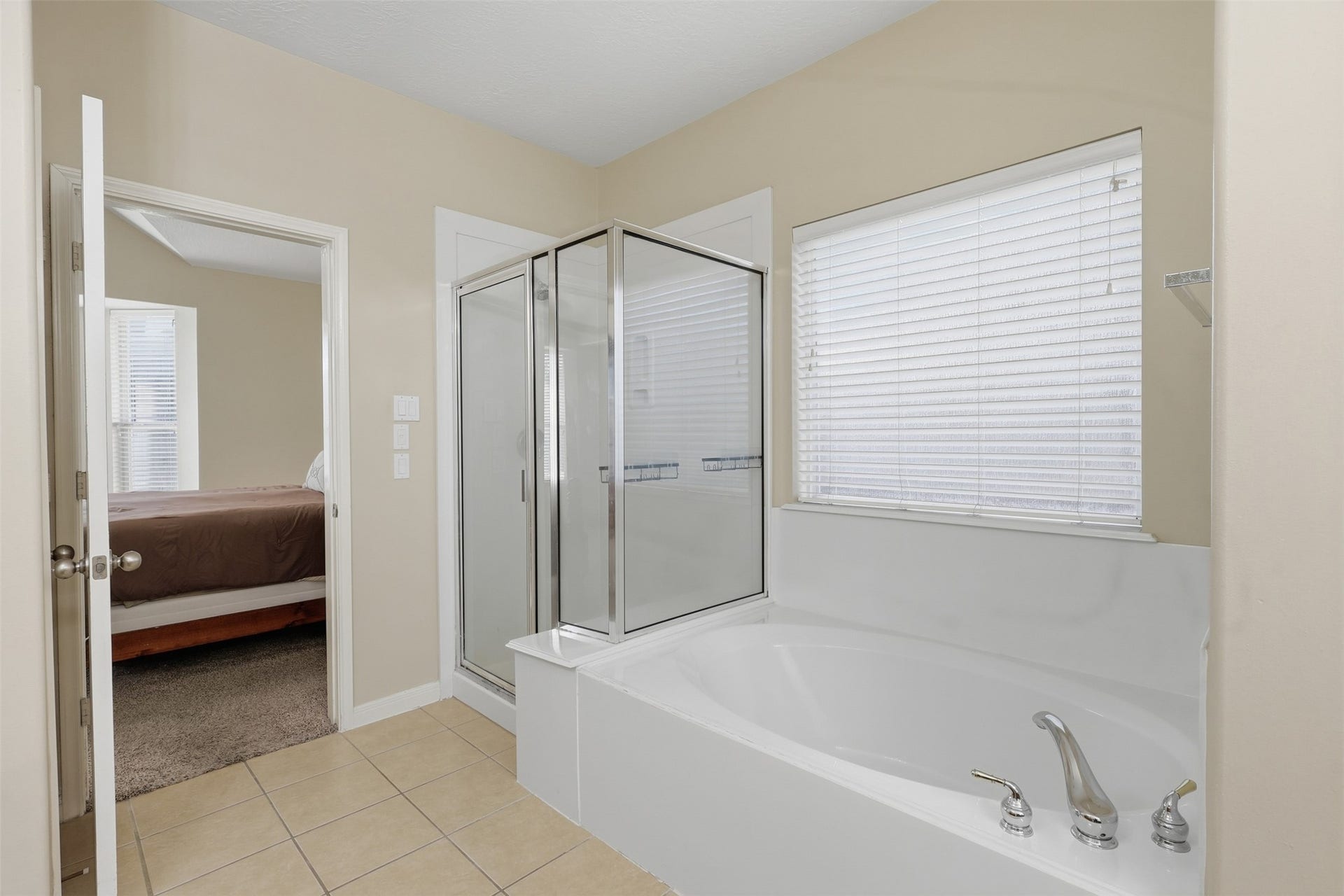 11404 Summit Bay Drive, Pearland, TX 77584 Beautifully appointed primary bath showcases the large soaking tub, separate glass-enclosed walk-in shower, dual vanity, and bright window. A spacious and inviting setting with plenty of room to start and unwind at the end of the day.