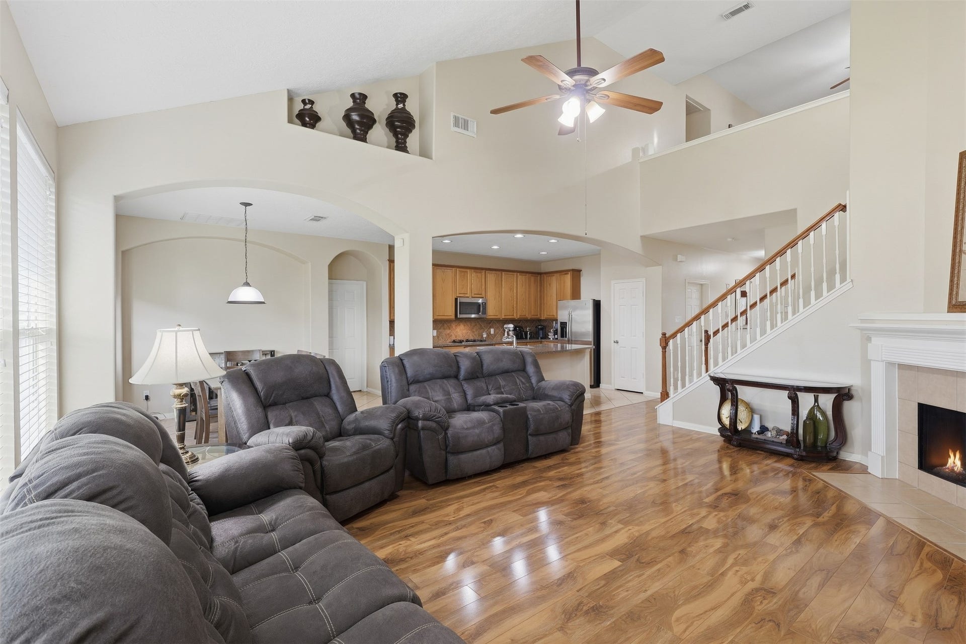 11404 Summit Bay Drive, Pearland, TX 77584 Spacious two-story family room offers an impressive open layout with soaring ceilings, beautiful wood-look flooring, a cozy corner fireplace, and a wall of windows that fills the space with natural light. The open connection to the kitchen makes entertaining effortless. Timeless floor plan!