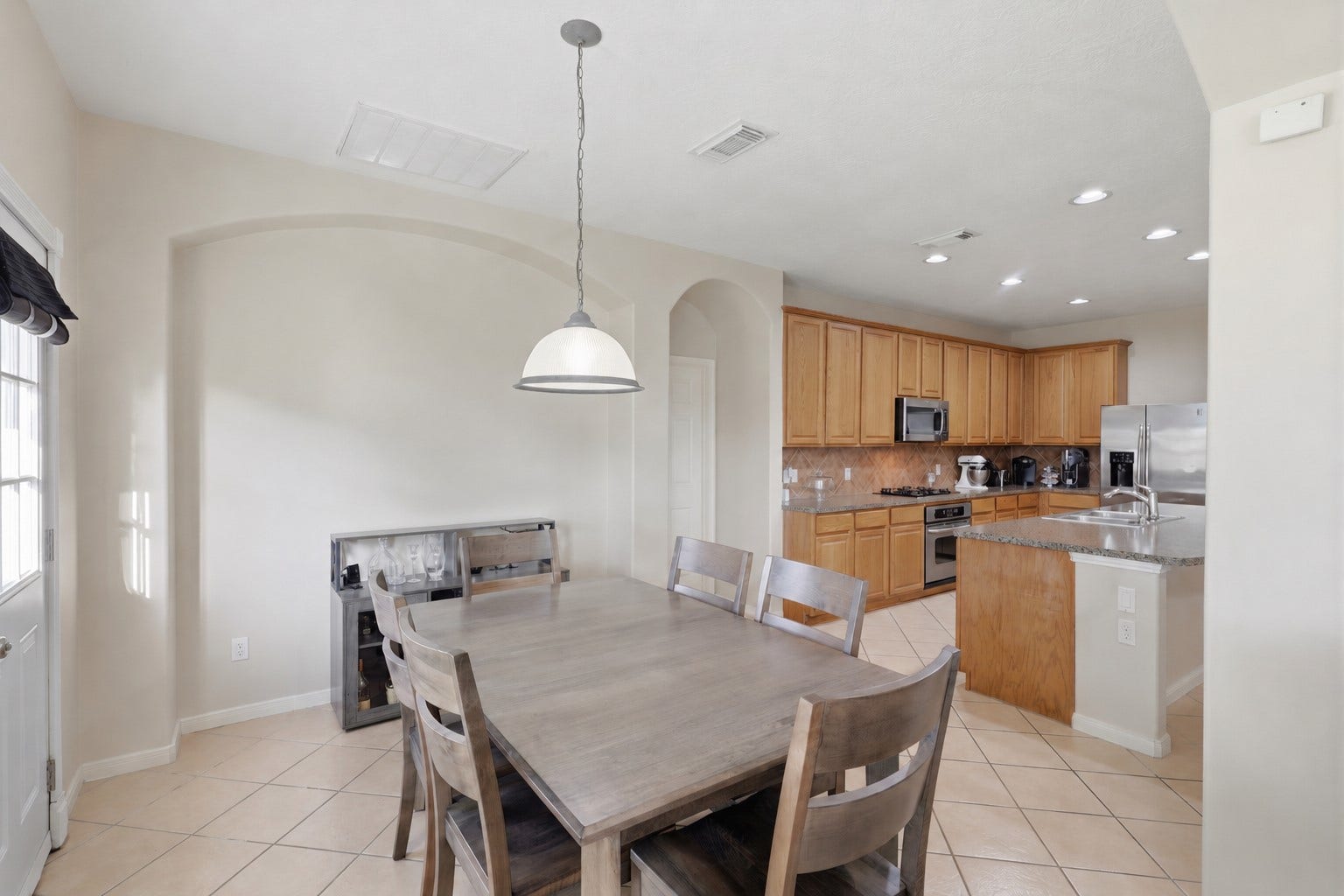 11404 Summit Bay Drive, Pearland, TX 77584 Bright breakfast area offers a comfortable setting for everyday dining, complemented by a stylish pendant light and abundant natural light. The open view into the spacious kitchen highlights the generous cabinetry, tile backsplash, and expansive island.