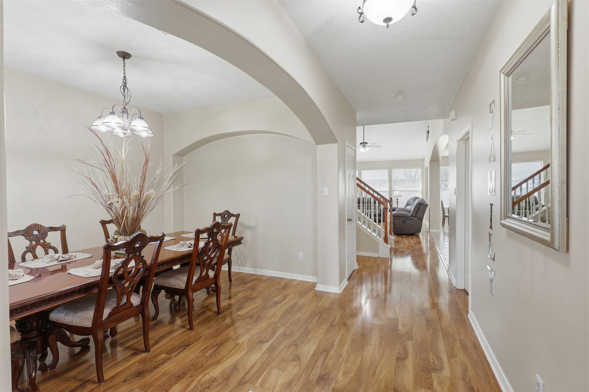 11404 Summit Bay Drive, Pearland, TX 77584 A beautiful first-floor view showcasing the home's welcoming entry and elegant formal dining room. Arched architectural details, soaring ceilings, wood-look flooring, and abundant natural light create an open and inviting introduction to the home, with easy flow toward the main living areas.