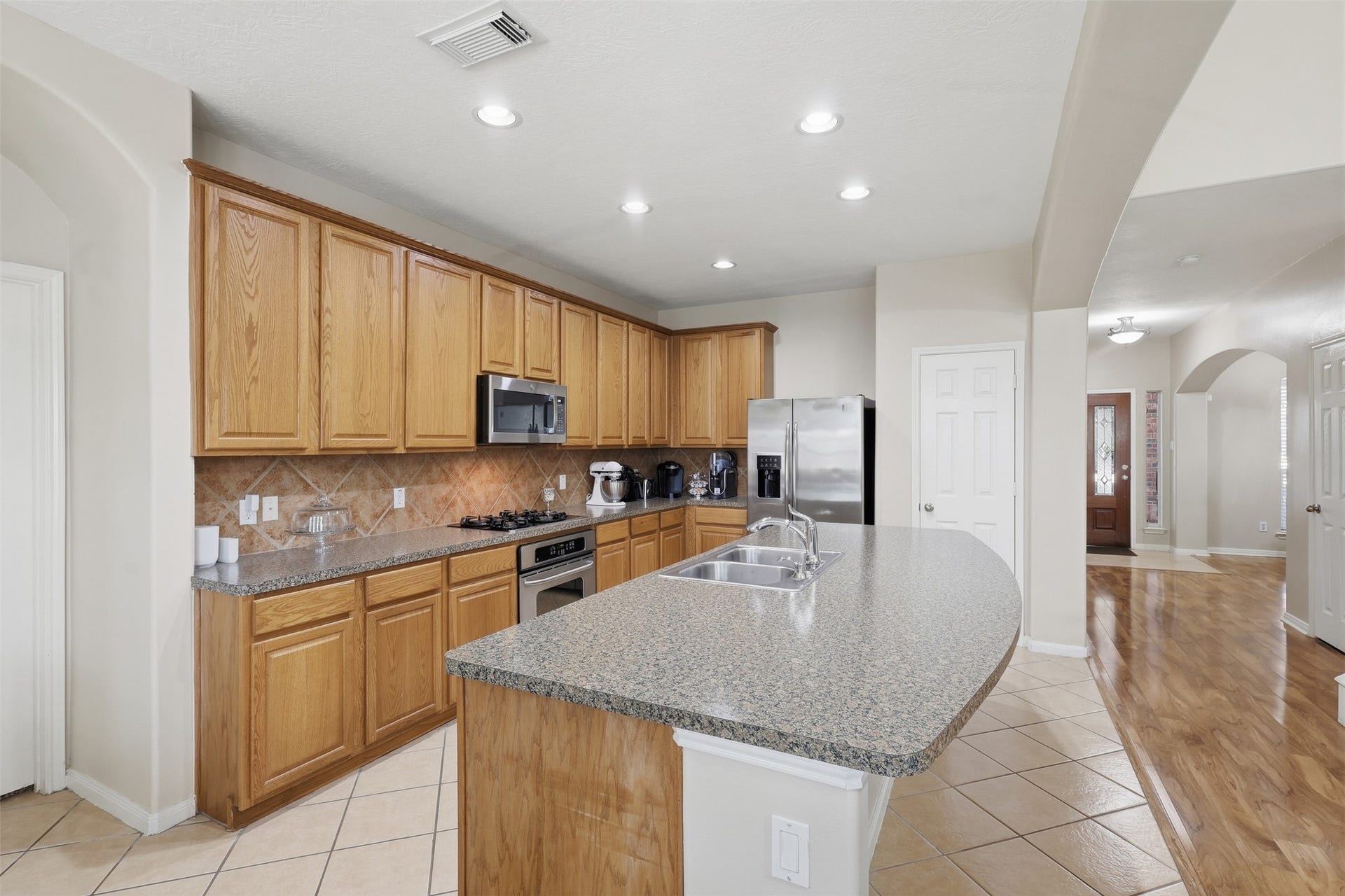 11404 Summit Bay Drive, Pearland, TX 77584 Beautifully appointed kitchen features abundant tall cabinetry, tile backsplash, built-in stainless-steel appliances, and a massive center island with generous workspace. The open design provides a seamless connection to the family room and breakfast area. Wait till you see the walk-in pantry! Make that call!