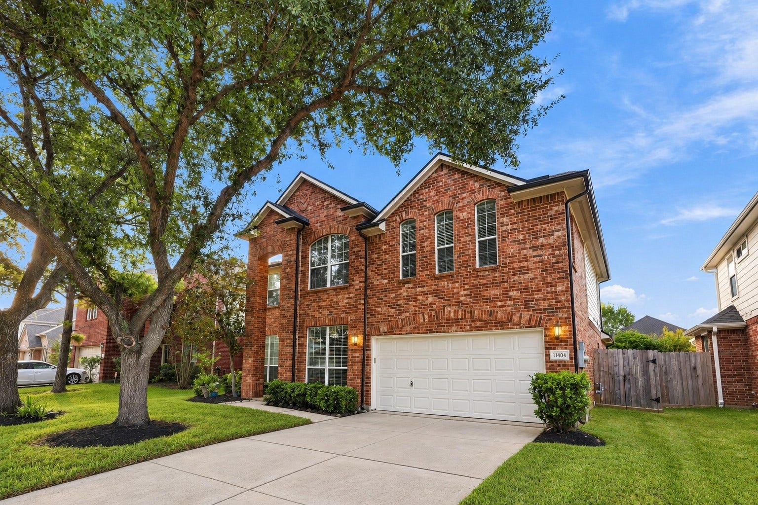 11404 Summit Bay Drive, Pearland, TX 77584 Charming brick elevation showcases a beautifully maintained front yard, mature shade trees, tall windows, and a generous driveway leading to the oversized 2.5-car garage. A wonderful first impression of this spacious Shadow Creek Ranch home!