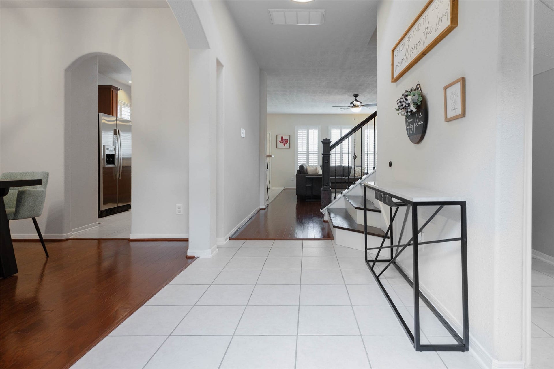 Step inside to a bright, welcoming entry where tile flooring, neutral finishes, and graceful arched openings introduce the homes flowing first-floor design. Rich wood flooring begins just beyond, adding warmth to the adjoining living spaces.