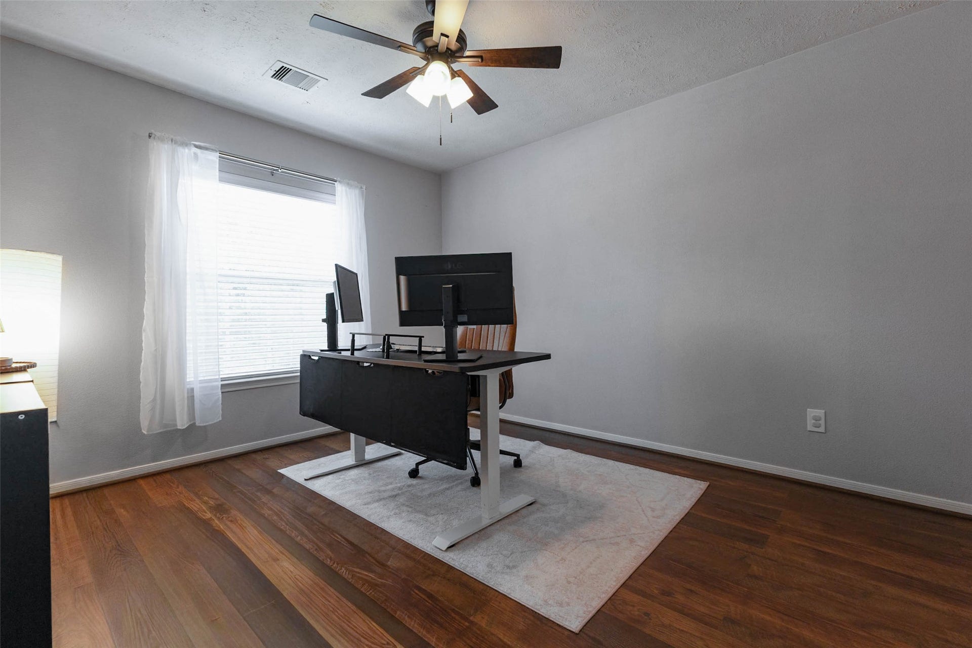 Another flexible secondary bedroom showcases its generous wall space, warm wood-look flooring, and large window. There is ample room for bedroom furnishings or a complete work-from-home setup.