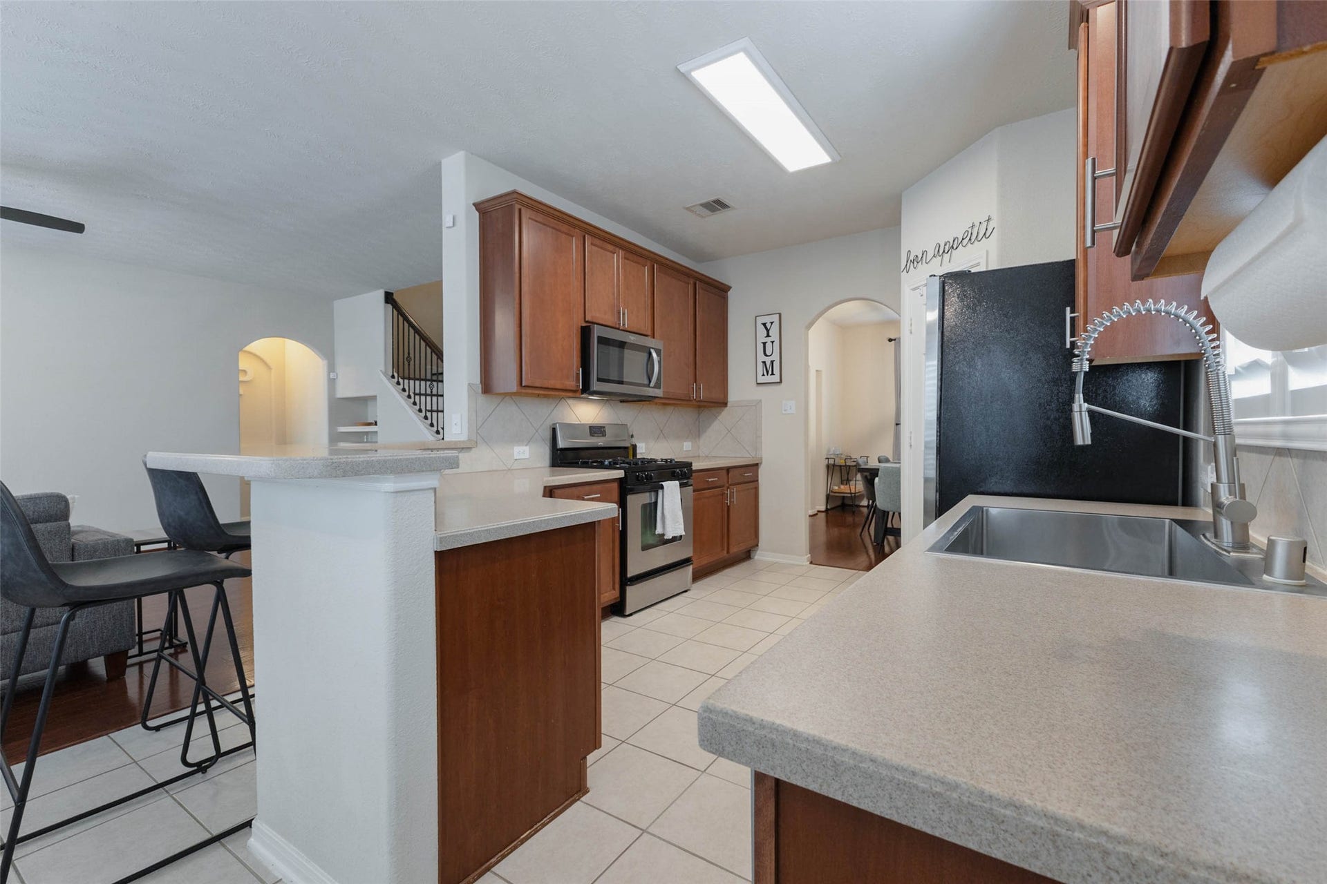 A generous raised breakfast bar provides additional seating and serving space while opening the kitchen toward the adjoining breakfast area and family room. Rich cabinetry, neutral finishes, and stainless steel appliances give the kitchen a timeless, cohesive look.