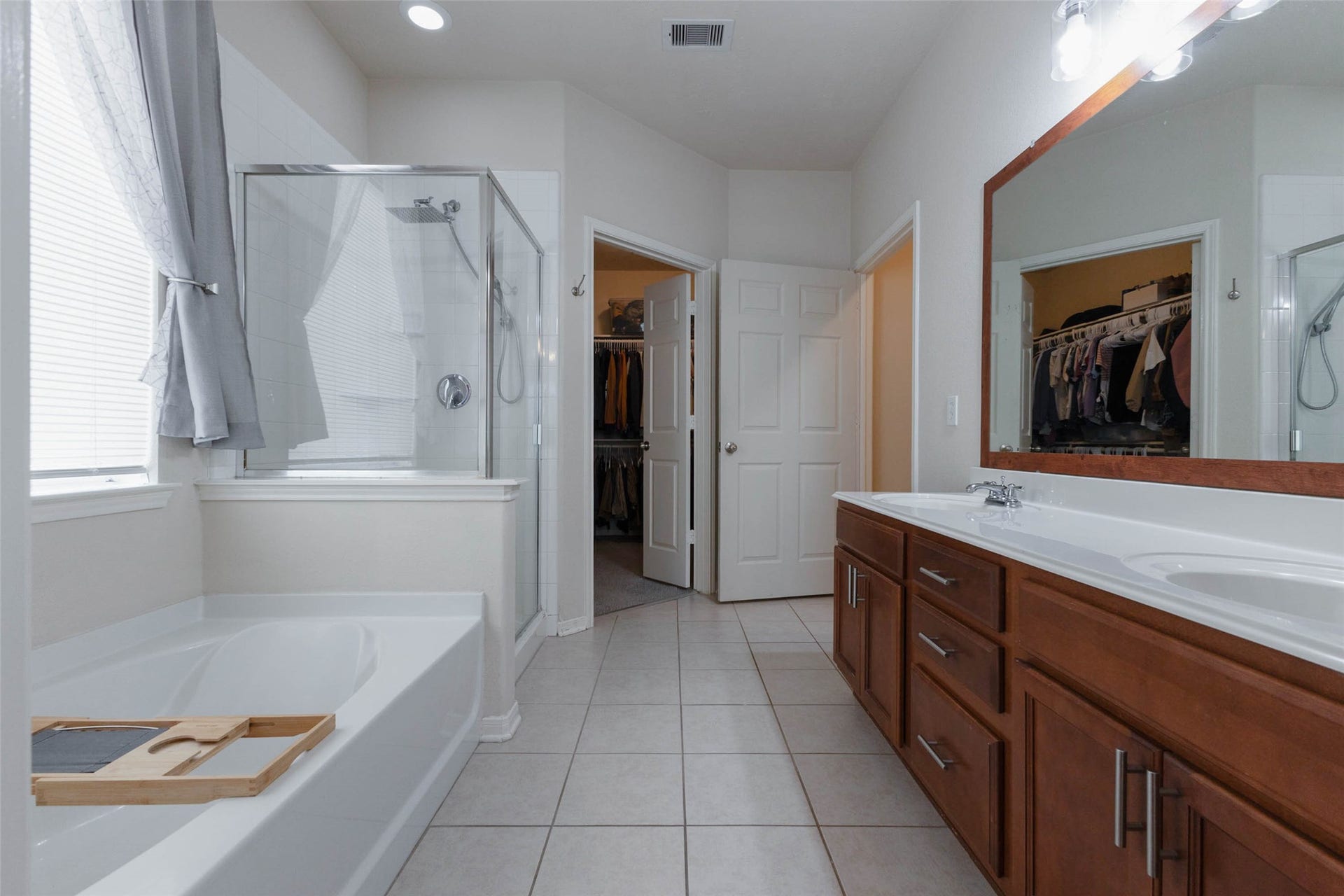 The spacious primary ensuite features a long dual-sink vanity with abundant cabinetry and counter space, along with a soaking tub and separate glass-enclosed shower for a comfortable, well-appointed retreat.