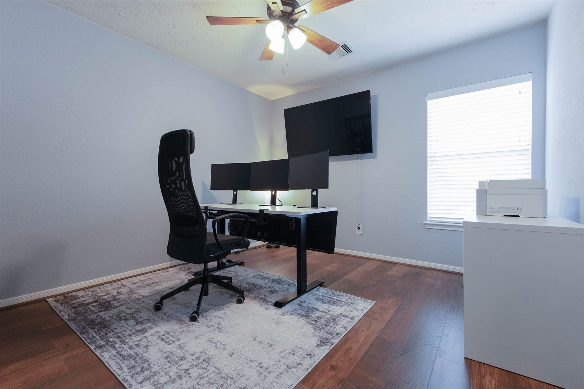 Currently arranged as a home office, this secondary bedroom offers wood-look flooring, a ceiling fan, and natural light from a large window. The flexible space can easily transition between bedroom, office, hobby room, or study depending on your needs.