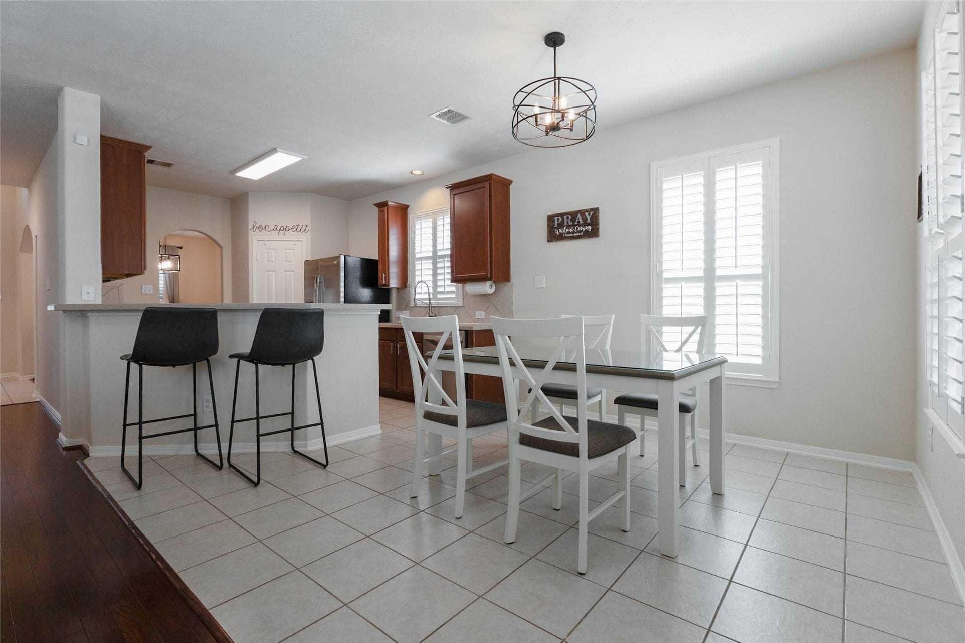 The casual dining area sits just beyond the extended breakfast bar, creating a natural gathering place beside the kitchen. Plantation shutters dress the surrounding windows and exterior door, filling the space with filtered natural light.
