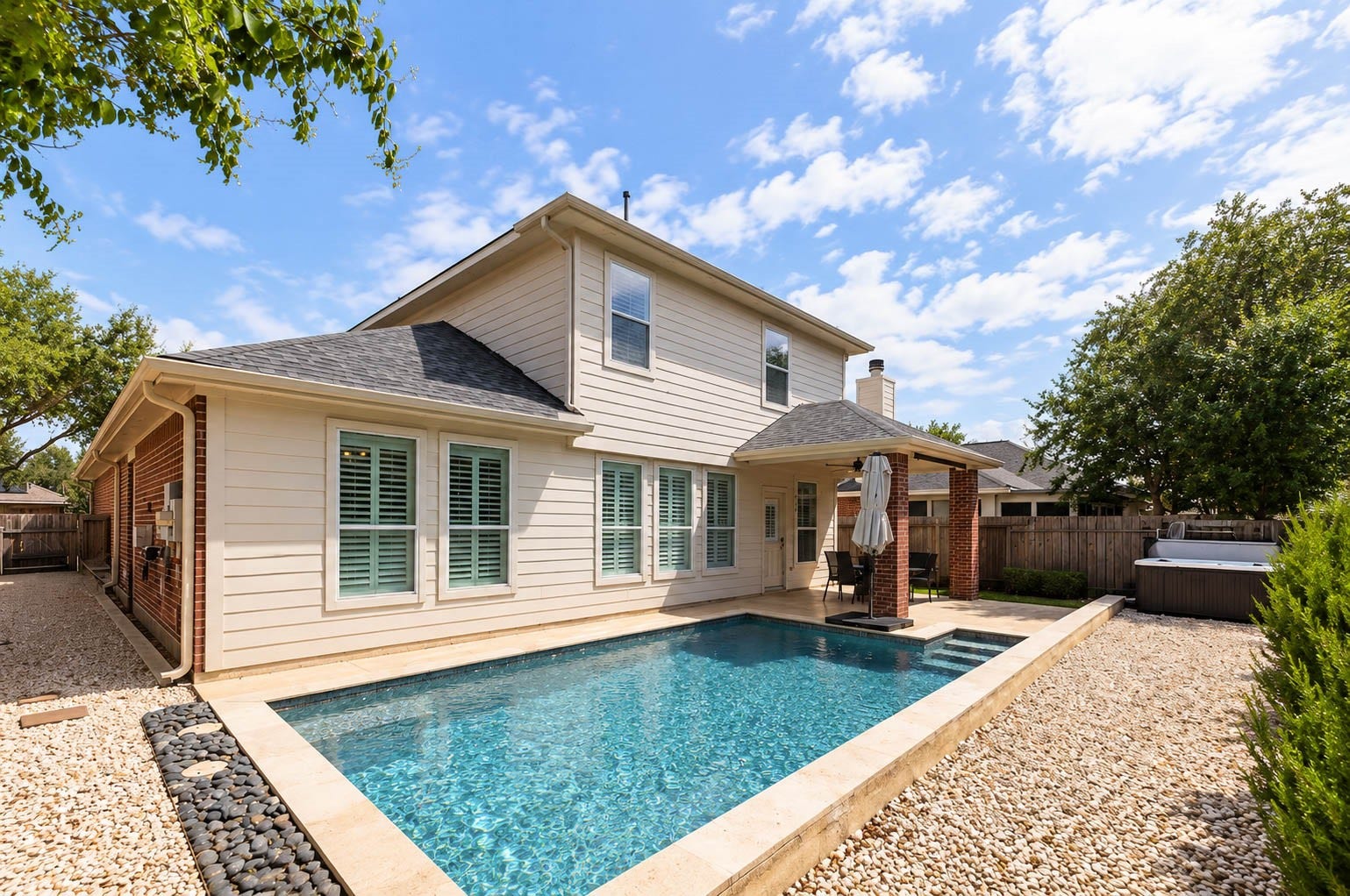 The backyard centers around a beautifully designed swimming pool framed by light stone coping and low-maintenance landscaping.