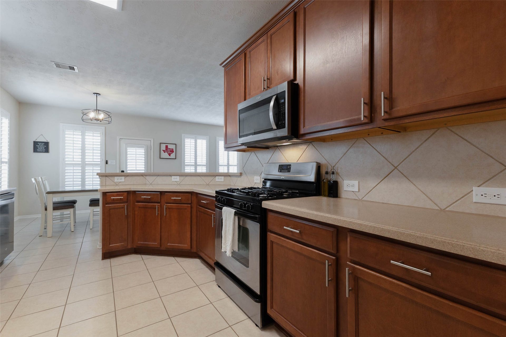 This perspective highlights the impressive amount of storage and workspace available throughout the kitchen. Expansive counters provide ample room for meal preparation and serving, while the raised breakfast bar extends the rooms functionality with additional casual seating.