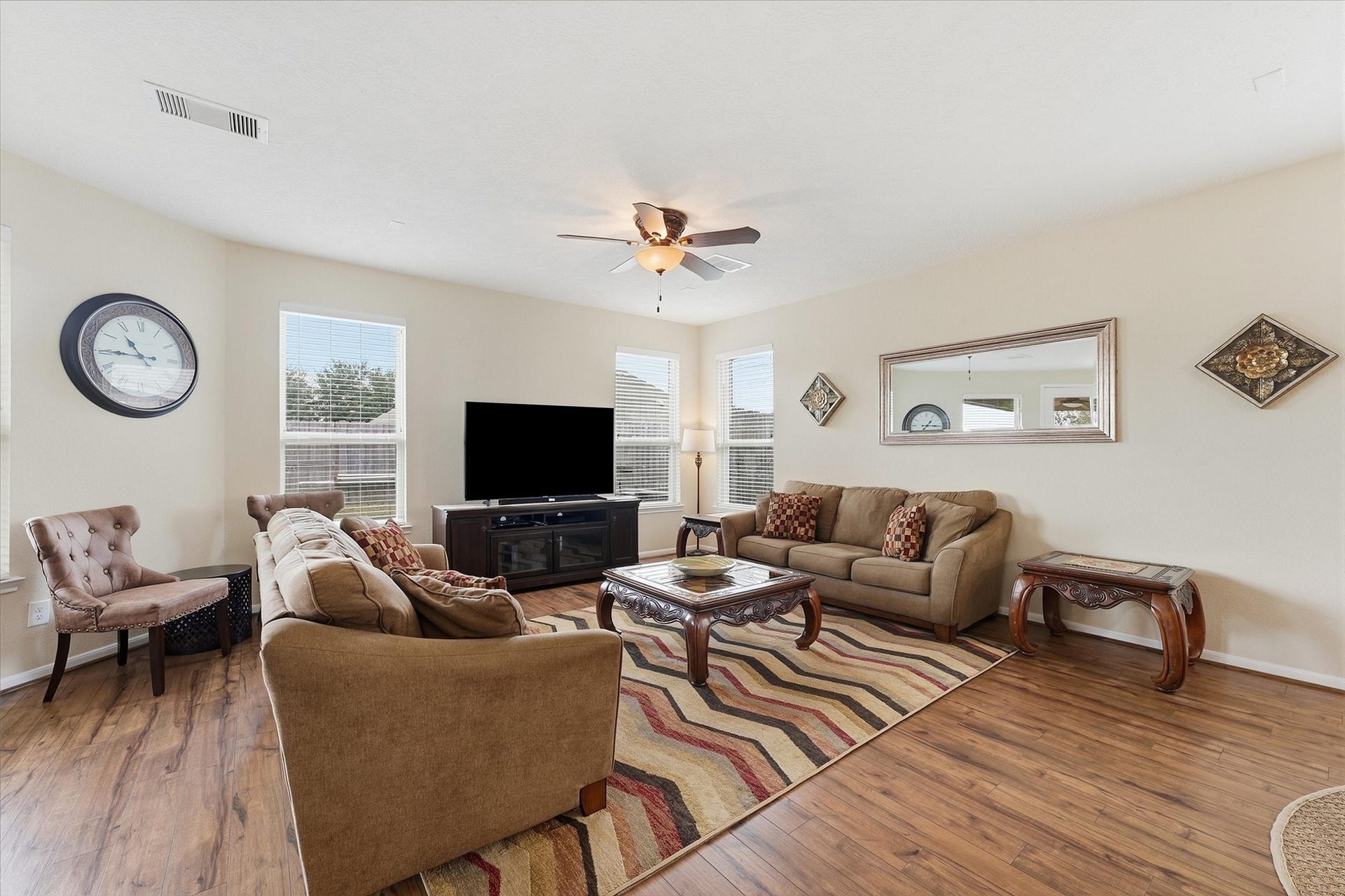 25522 Brentmoor Drive, Porter, TX 77365 Spacious, light-filled family room featuring wood-look flooring, a lighted ceiling fan, multiple picture windows, and direct glass-door access to the backyard.