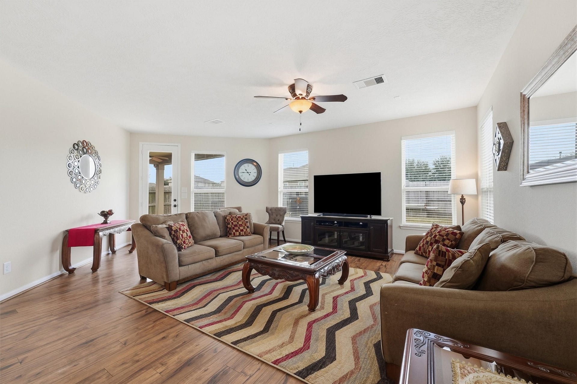 25522 Brentmoor Drive, Porter, TX 77365 Spacious, light-filled family room featuring wood-look flooring, a lighted ceiling fan, multiple picture windows, and direct glass-door access to the backyard.